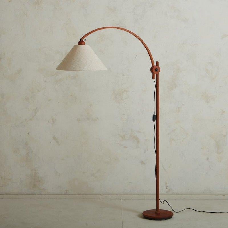 A 1970s German floor lamp constructed with teak wood featuring beautiful graining. This sleek lamp has a round base and an adjustable curved stem, allowing for a range of positions. It retains its original cream fabric shade and black acrylic inline