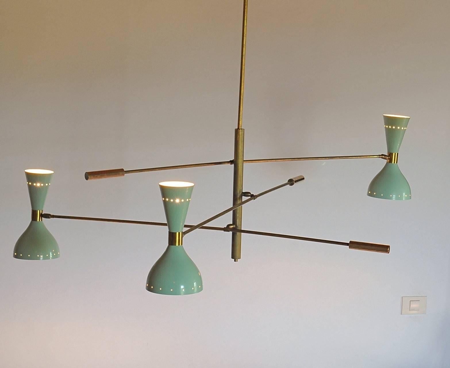 Ce lustre reprend la structure des bras des autres lustres à trois bras de la gamme. La nouveauté réside dans le fait que les points d'articulation de la tige centrale ne sont pas sur la même ligne, mais décalés de manière à ce que la position