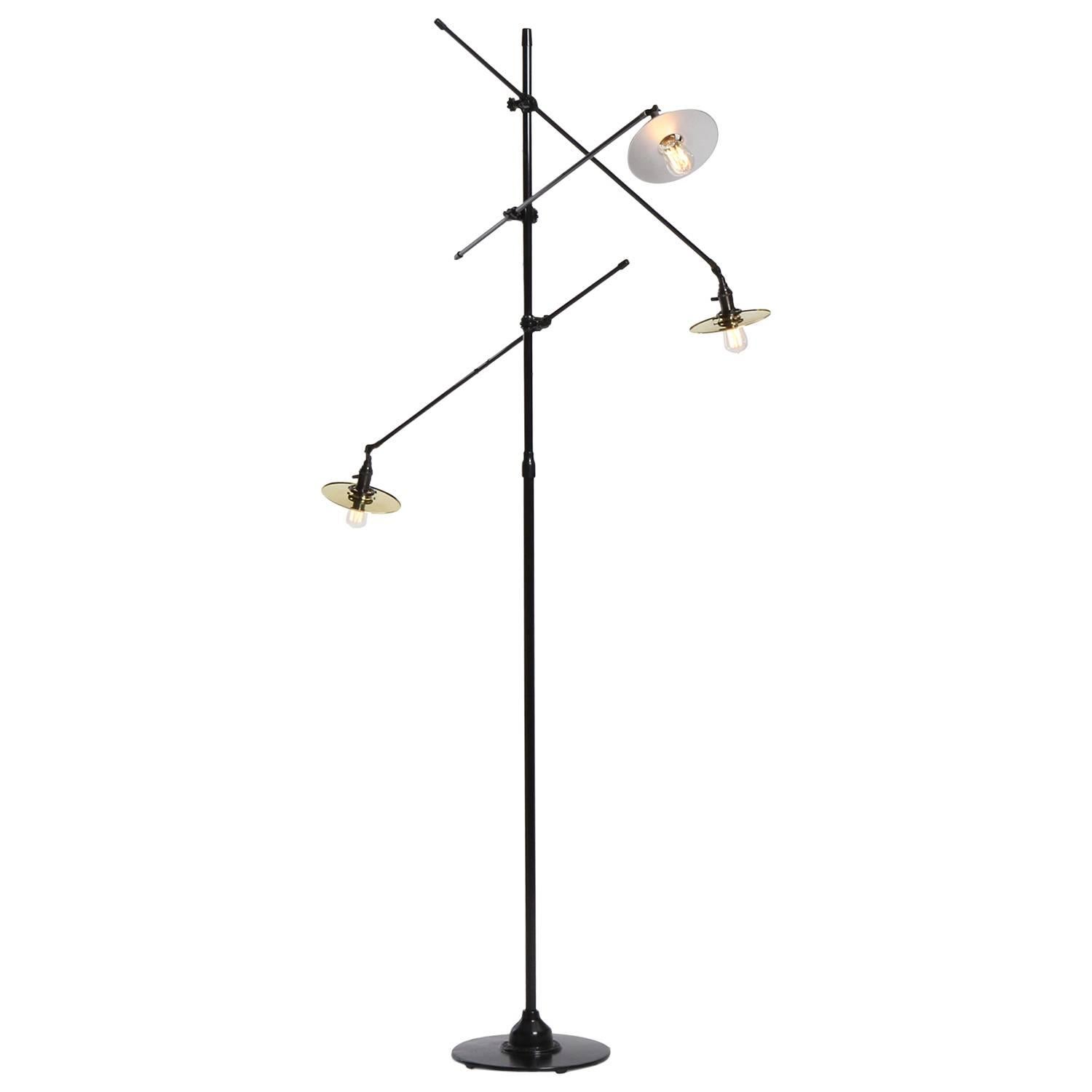A 3-arm Industrial style floor lamp manufactured by O.C. White featuring impressively scaled and finely fabricated parts in patinated steel and polished brass. Lamp features three articulating arms that also can be adjusted vertically, rising from a