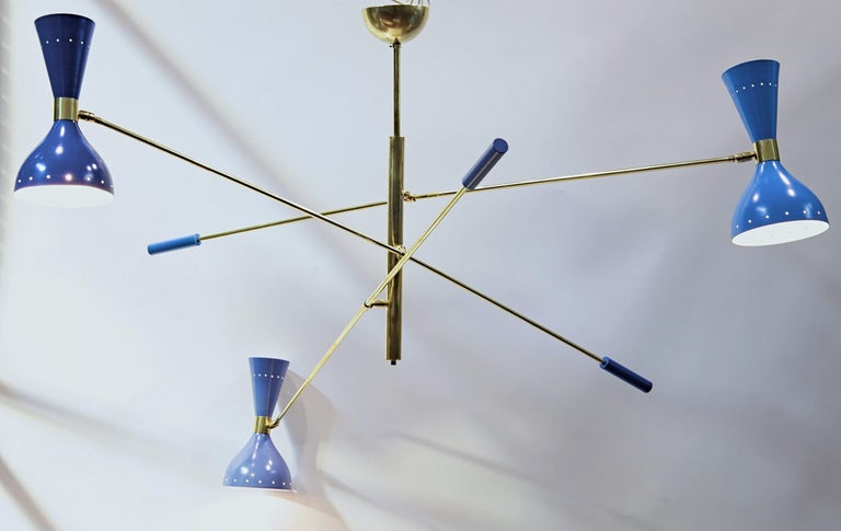 Bespoke chandelier with three arms that are counterbalanced. That allows to move the arms up and down. The heads are on a pivotting joint to they can reach any desired angle.

This chandelier features threw different blue color on the shades,