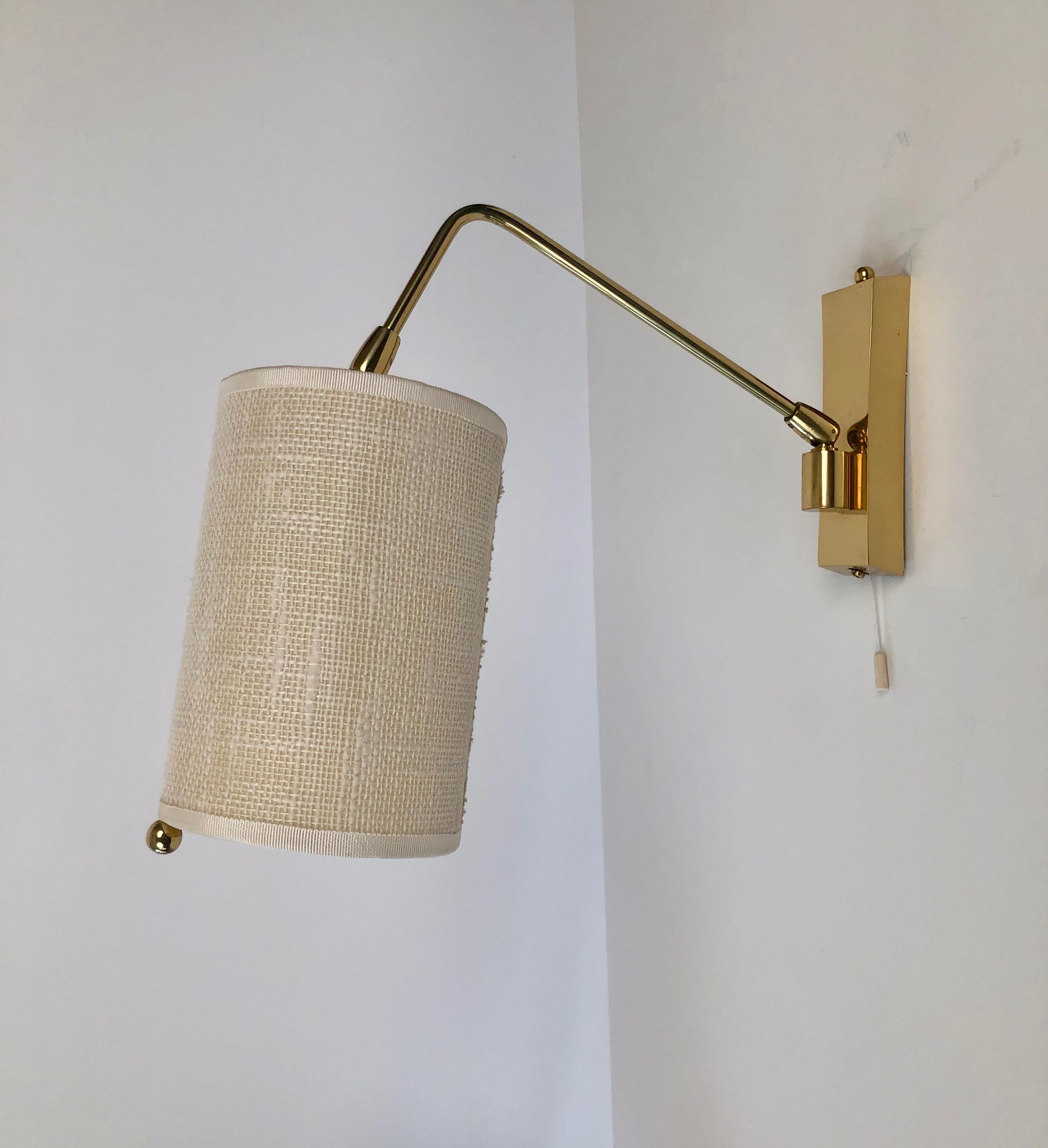 Minimalistic  wall light in brass, adjustable from two swivel joints: on the base and on the 
end of the arm, by the bulb. The shade is original in a light cream coloured linen.
The lamp is very precisely made, manufactured by J. T. Kalmar,
