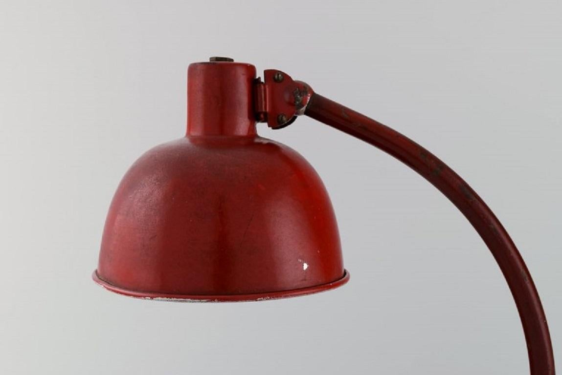 Adjustable work lamp in original red lacquer. 
Industrial design, mid-20th century.
Height: 40 cm.
The foot measures: 20 x 13.5 cm.
Screen diameter: 17 cm.
In excellent condition.
Minor signs of use.