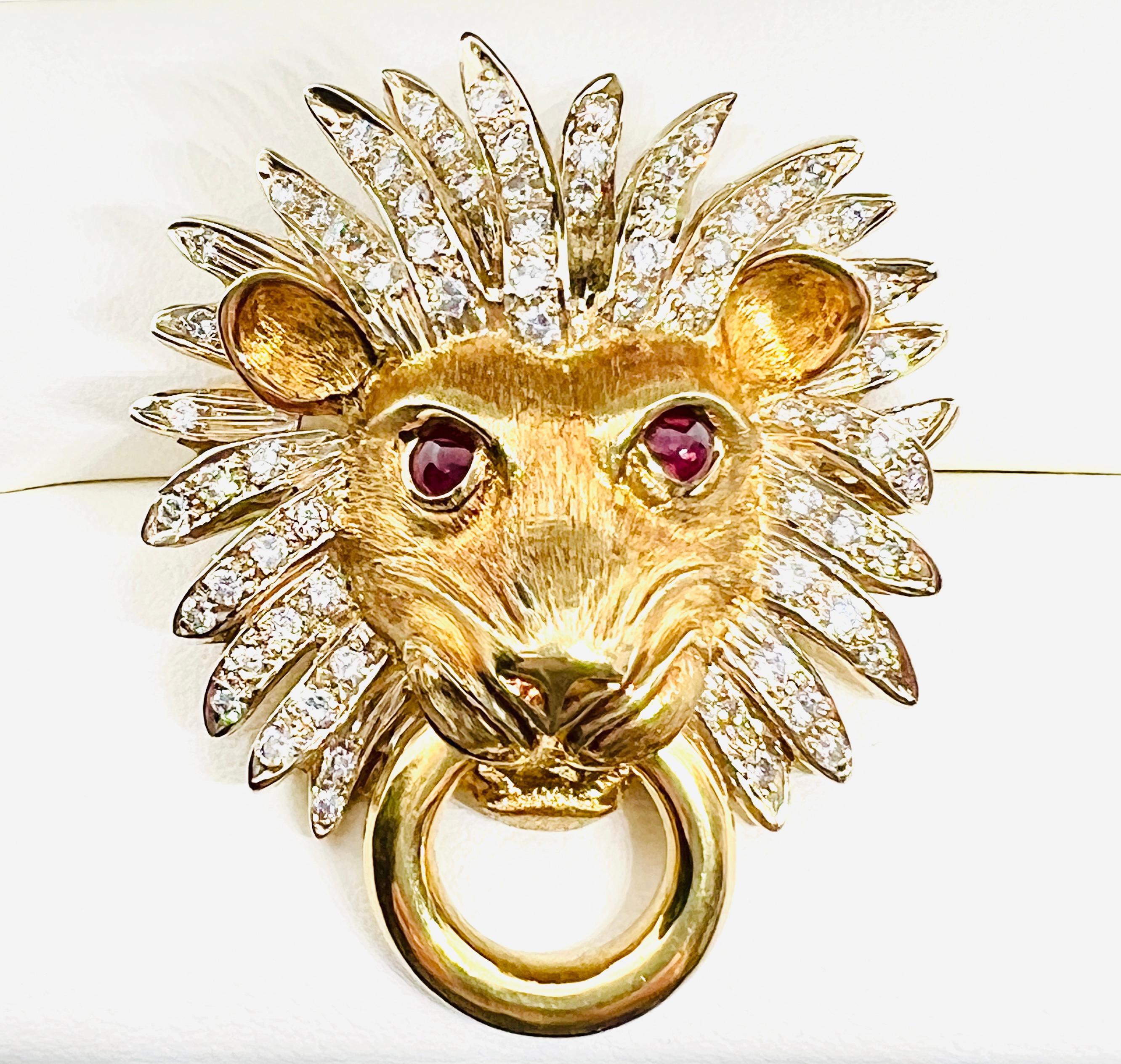 Gorgeous Adler 18K Yellow Gold Lionshead Doorknocker pendant / enhancer. This Vintage piece features 76 diamonds in the lion's mane and two cabochon rubies as the eyes. The piece measures 1.75 inches by 1.25 inches and weighs 30.4 grams. The Adler