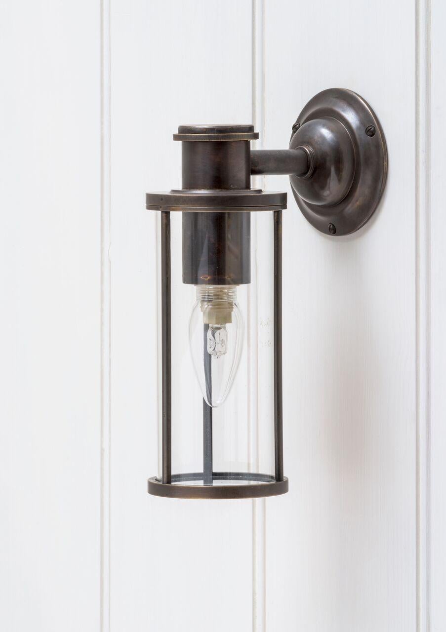 A cylindrical lantern, inspired by Industrial design of the 1920s. Supported on a heavy cast brass wall mounted fixture. Please note - to conform with US regulations the fixture will be supplied on a backplate as illustrated in image no. 10. The