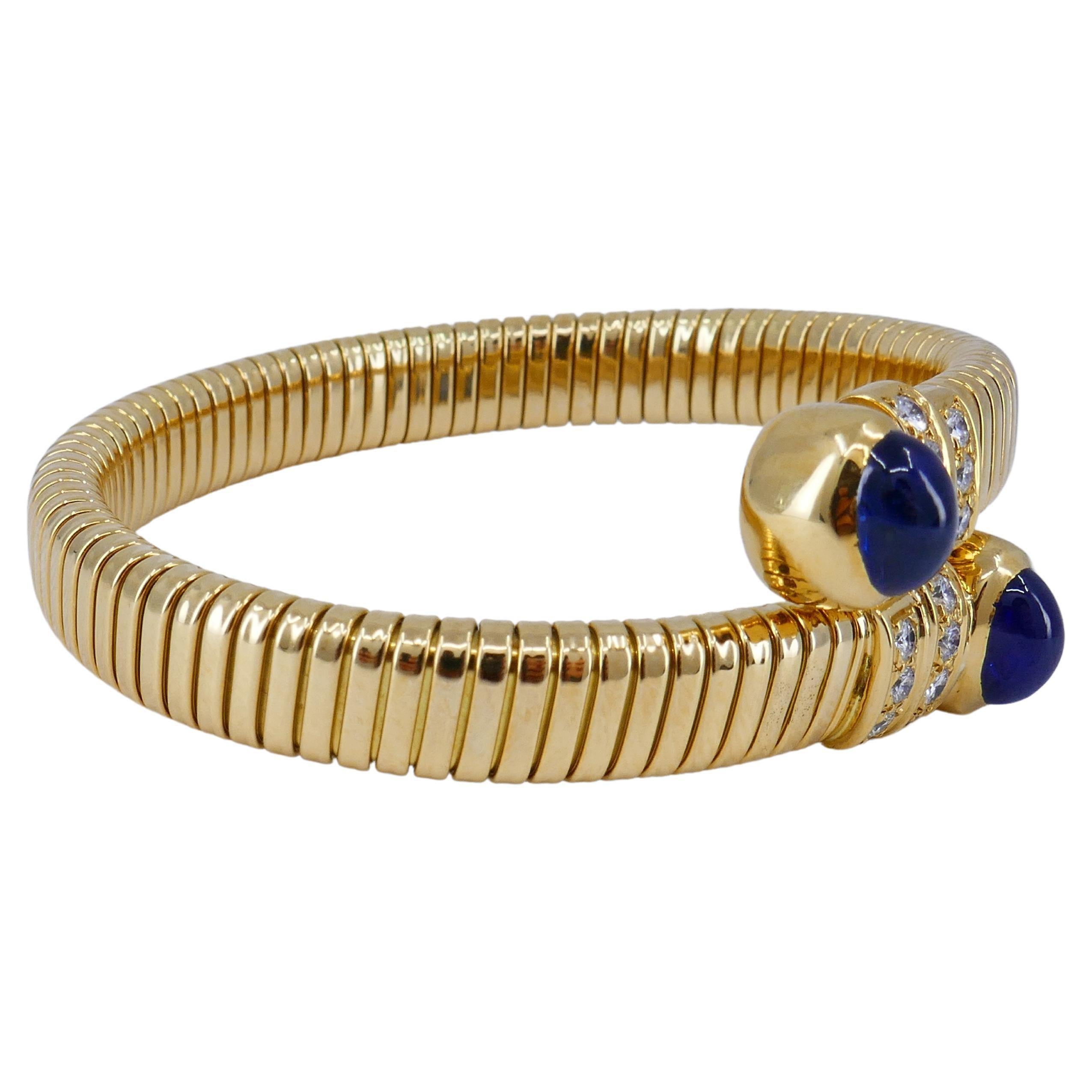 Un bracelet tubogas en or 18k d'Adler Geneve, avec saphirs cabochons et diamant.
Les diamants sont de taille brillant, sertis en canal. Les pierres sont disposées en deux rangées horizontales. Le bracelet est conçu comme un tubogas enveloppant, une
