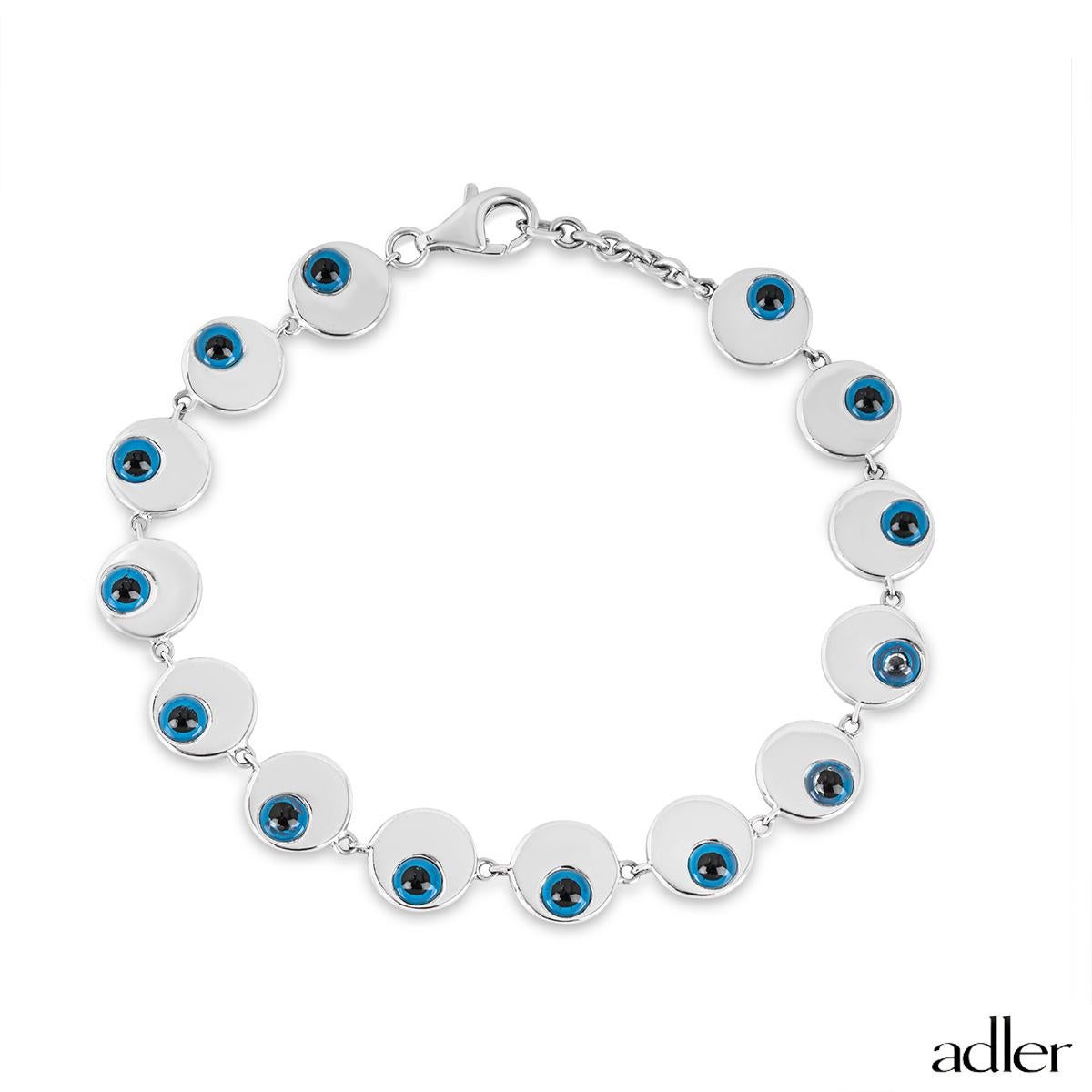 An 18k white gold enamel eye bracelet by Adler. The bracelet is composed of 14 circular motifs each set around the edge with a raised blue enamel eye. The bracelet measures 7 inches in length and features a classic lobster clasp with a gross weight