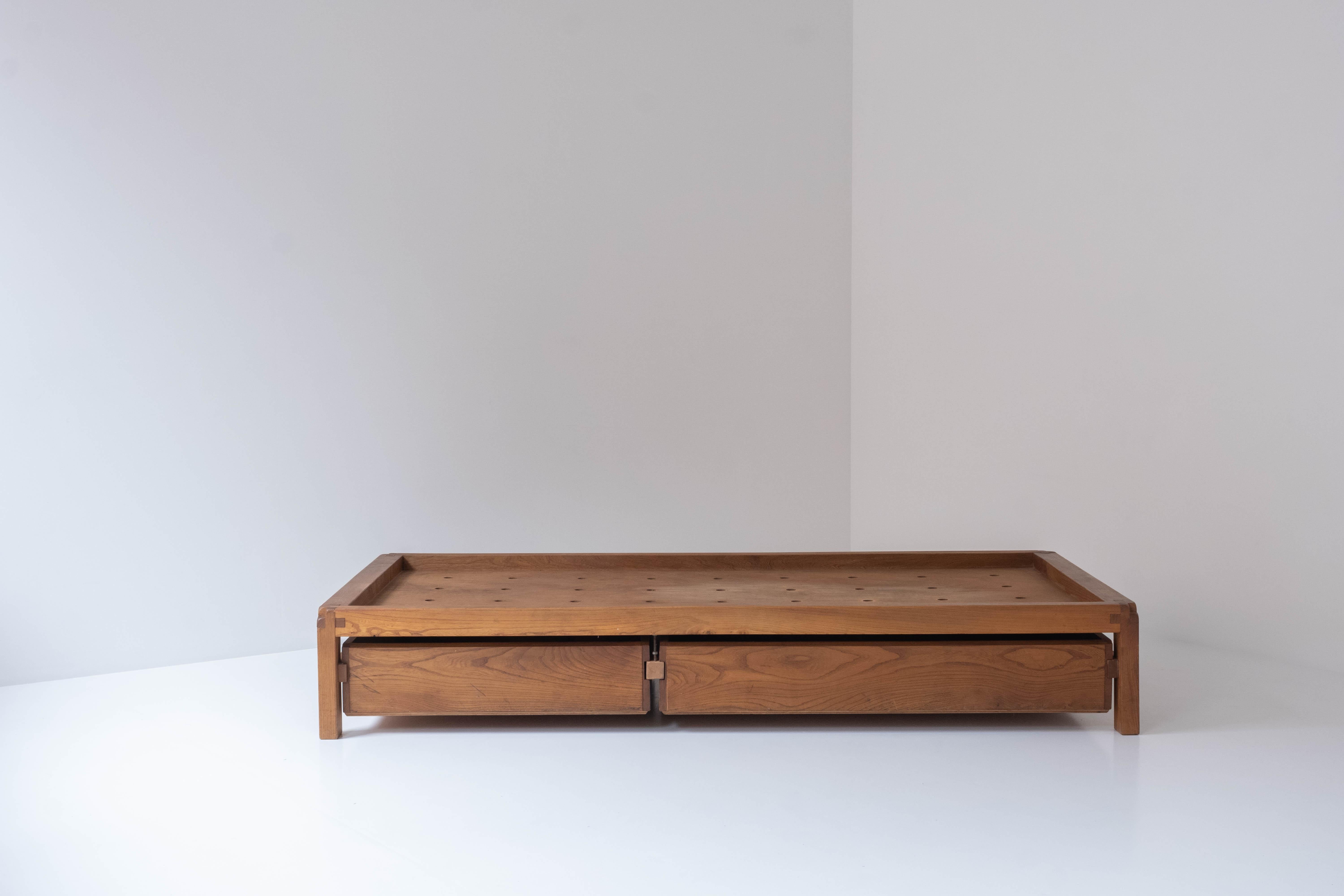 Admire this daybed model ‘L03’ by Pierre Chapo, designed and manufactured in his own workshop in France around 1965. This piece is fully handmade in solid elm wood and has a rich and warm overall patina. A set of two drawers underneath preserving a