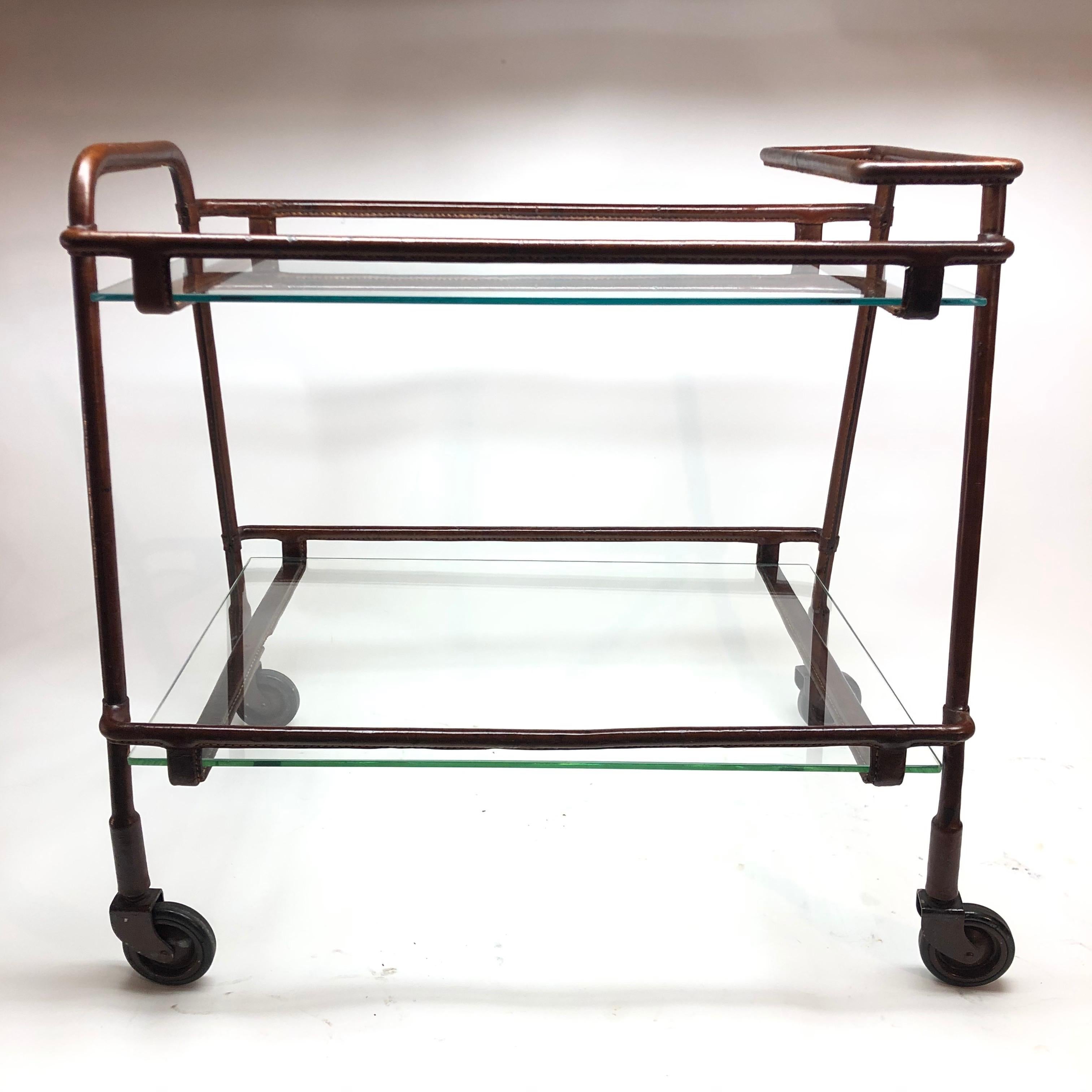 Jacques Adnet iron and leather covered bar cart / trolley. With 2 glass shelves. One stretcher has been patched as seen in photos. An extraordinary collectible piece.