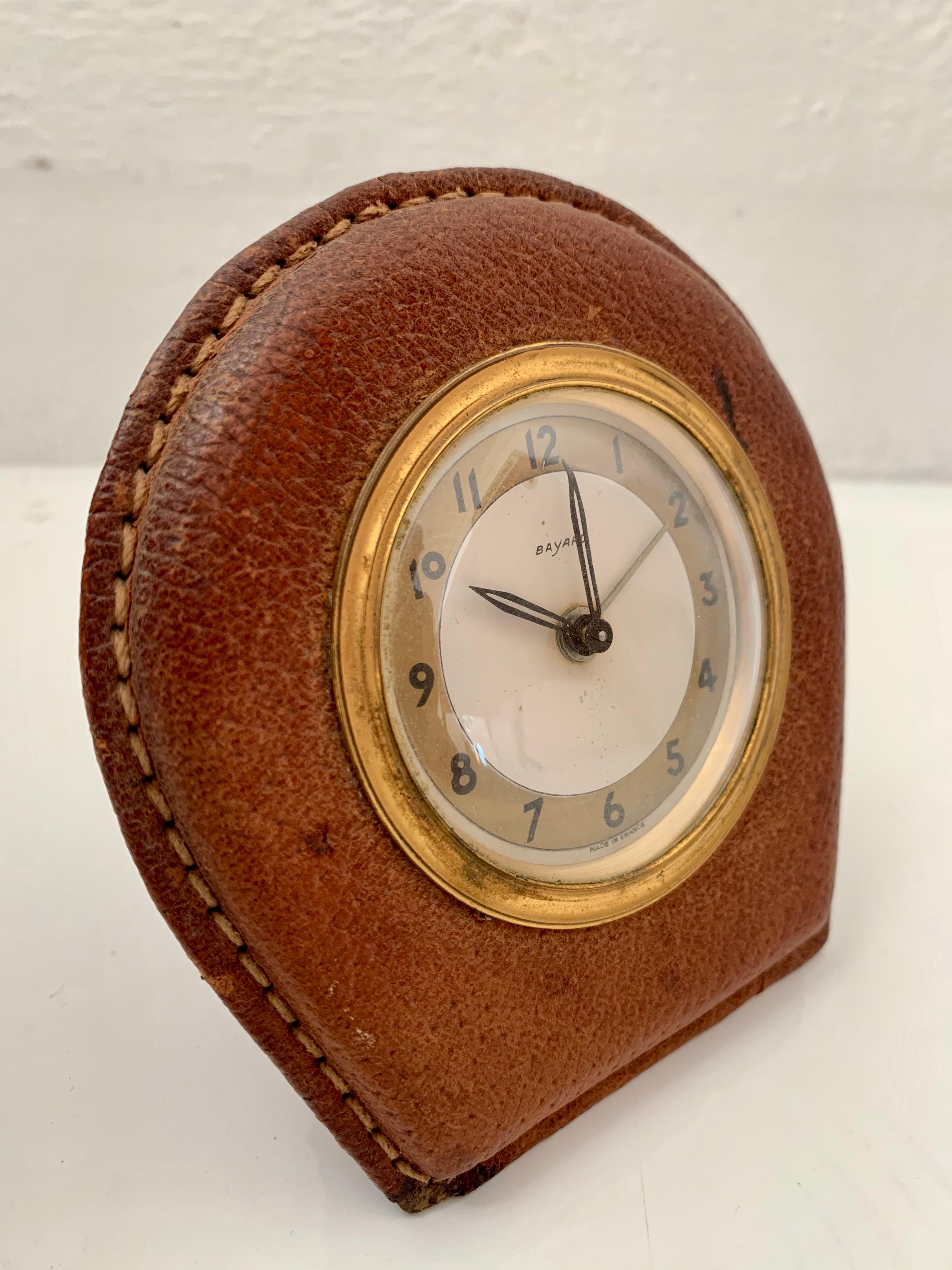 Handsome French saddle leather desk clock by Bayard in the style of Jacques Adnet. Excellent vintage condition. Keeps time and has an alarm. Great patina to brass and leather.