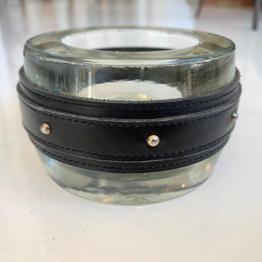Leather, brass and glass ashtray in the style of Jacques Adnet. Saddle leather frame with brass studs. Inset glass dish made by Val St Laurent in Belgium, founded in 1826. Great tabletop object. Great vintage condition.