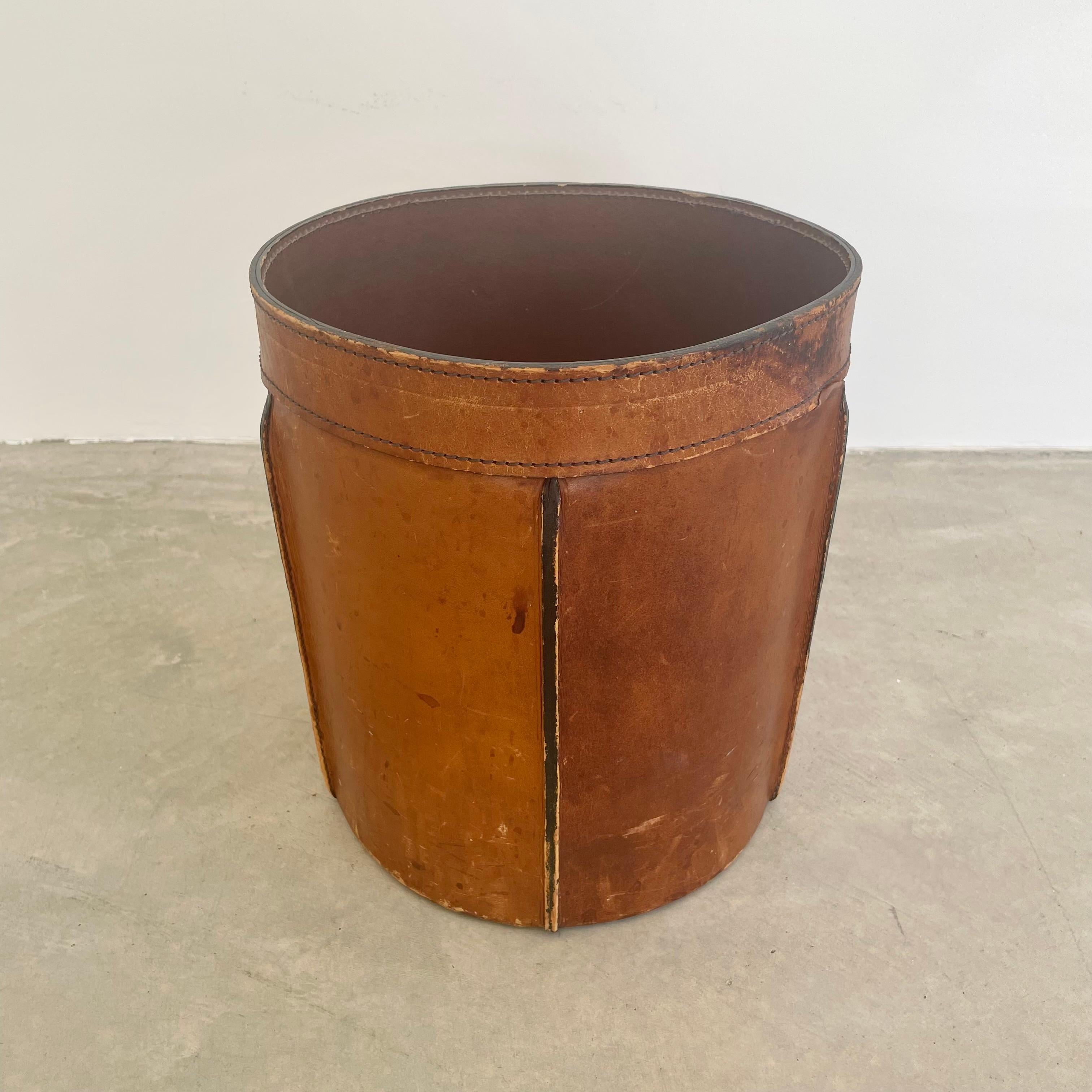 Gorgeous 1960s waste bin with ridged seams made out of brown cowhide leather. Thick stitching gives this piece a slight Adnet style thus elevating it's appearance. Beautiful scuffs and water marks give this piece a totally unique patina and