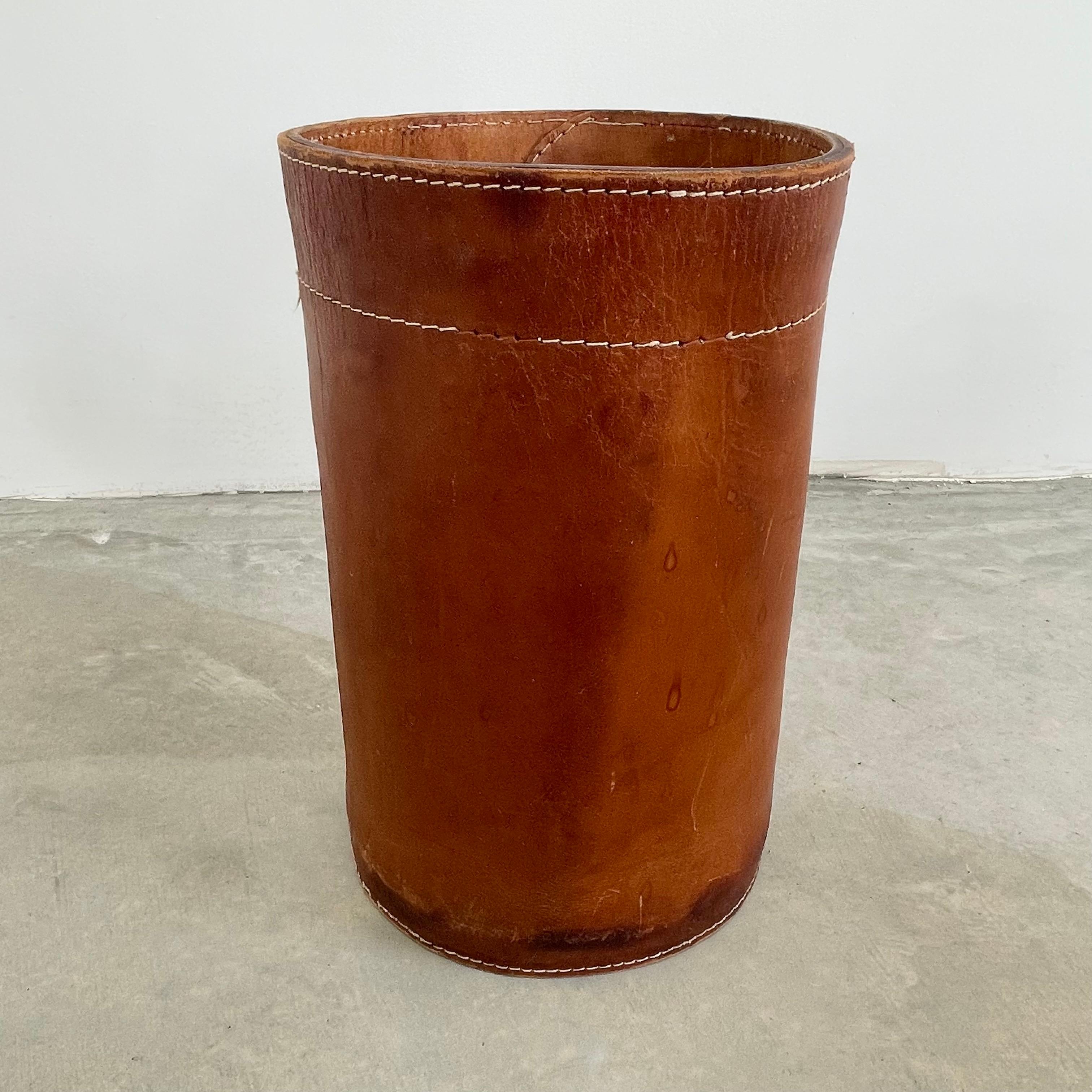 Handsome saddle leather waste bin in the style of Jacques Adnet. Circa 1950s. Great color and age. Inset, removable wooden basket to collect waste. Staining and age as shown. Great patina.