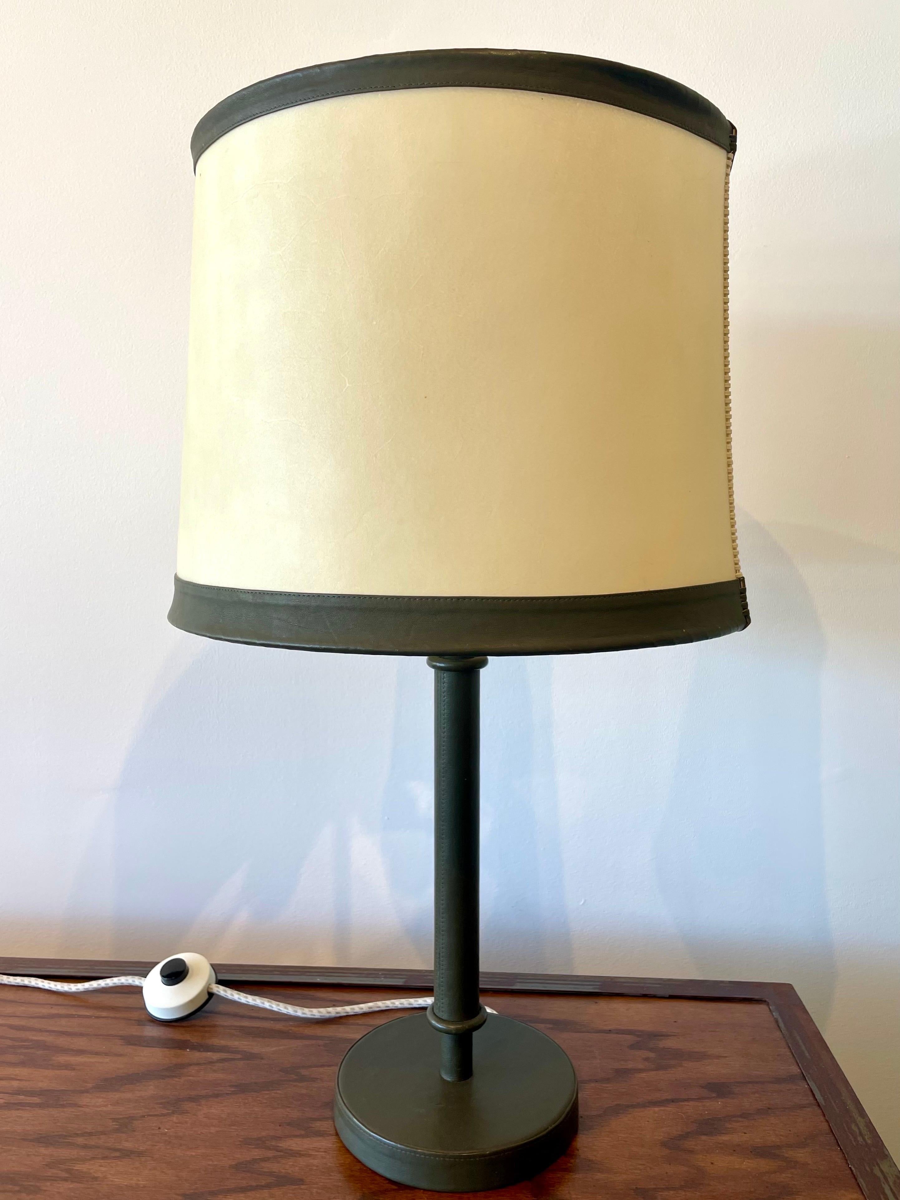 An exquisitely crafted stitched green leather table lamp with original parchment and leather trimmed lamp shade. This is rewired for US and in phenomenal vintage condition. NOTE: shade diameter 16 inches.
