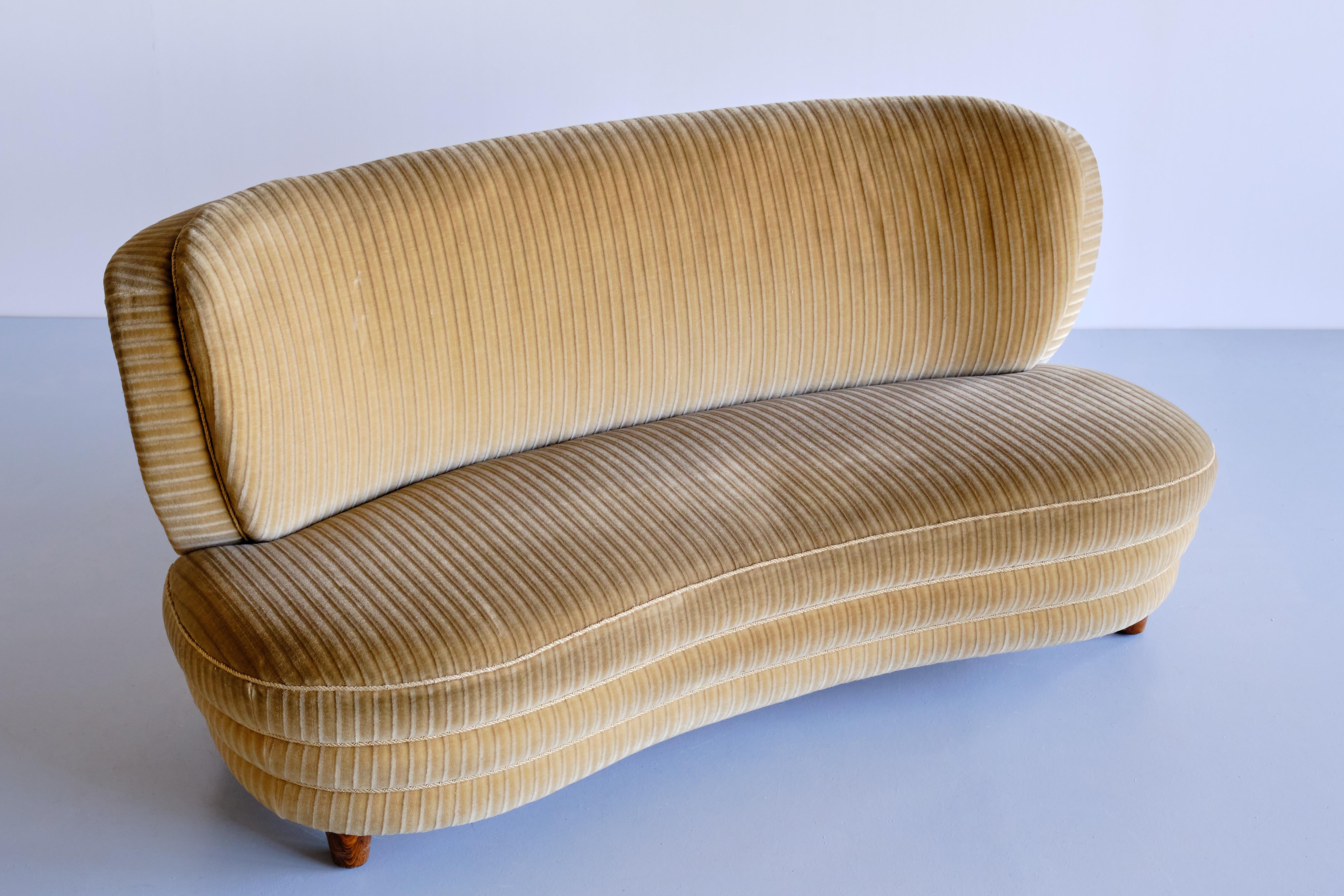 This curved sofa was designed by Adolf Wrenger and produced by his company in Lippe, Germany in the early 1950s. The curved shape and the round lines of both the backrest and seat give the sofa a striking and elegant feel. The seat appears to be