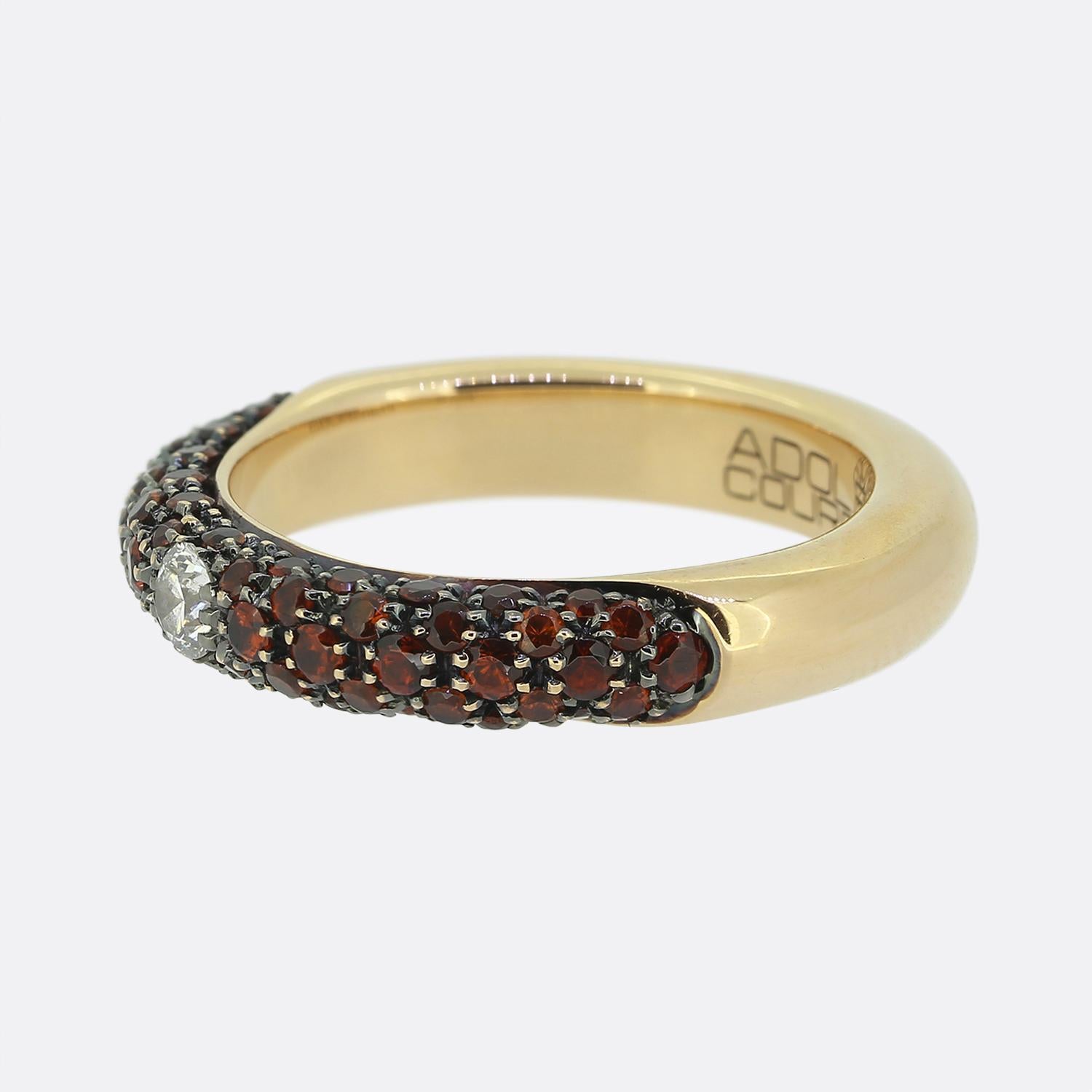 Here we have a striking 18ct rose gold band ring by Adolfo Courrier. At the centre of the face we find a single bright white round brilliant diamond set in an 8 clawed setting which sits surrounded by three rows of vibrant orange sapphires on either