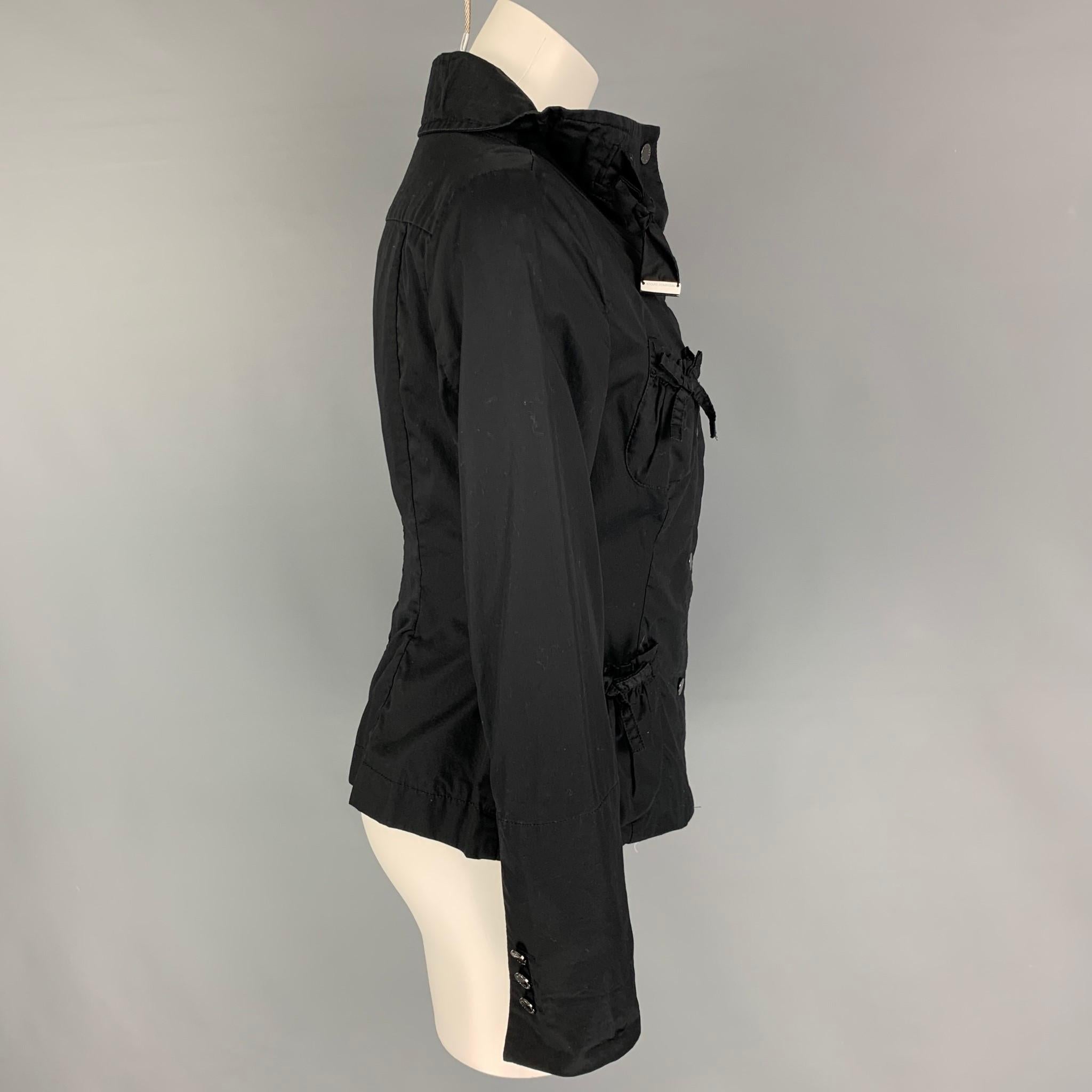 ADOLFO DOMINGUEZ jacket comes in a black cotton featuring a high neck, patch pockets, bow details, and a snap button closure 

Very Good Pre-Owned Condition.
Marked: 38

Measurements:

Shoulder: 16 in.
Bust: 36 in.
Sleeve: 24.5 in.
Length: 21 in. 
