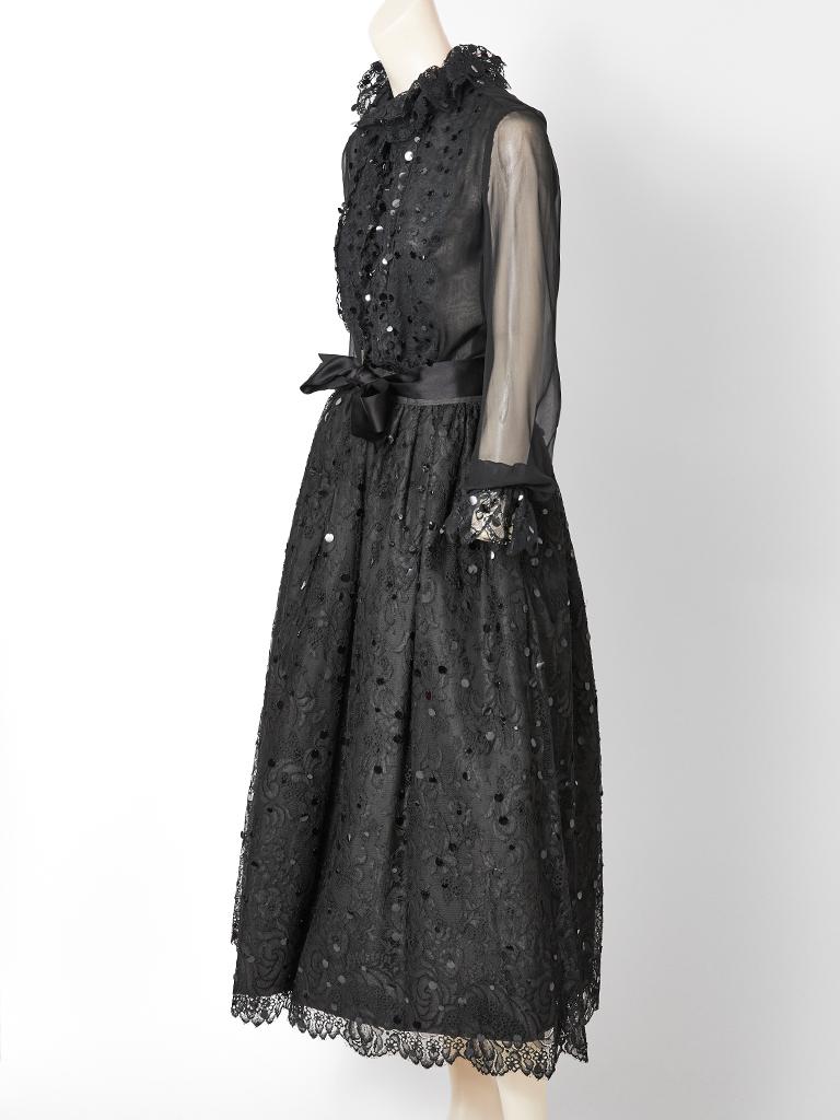 Adolfo, two piece lace and sequined evening ensemble having a lace blouse with a lining at the bodice and sheer chiffon sleeves. Blouse is embellished with black paillettes and a lace ruffled collar and cuffs. Lace skirt is gathered at the waist,