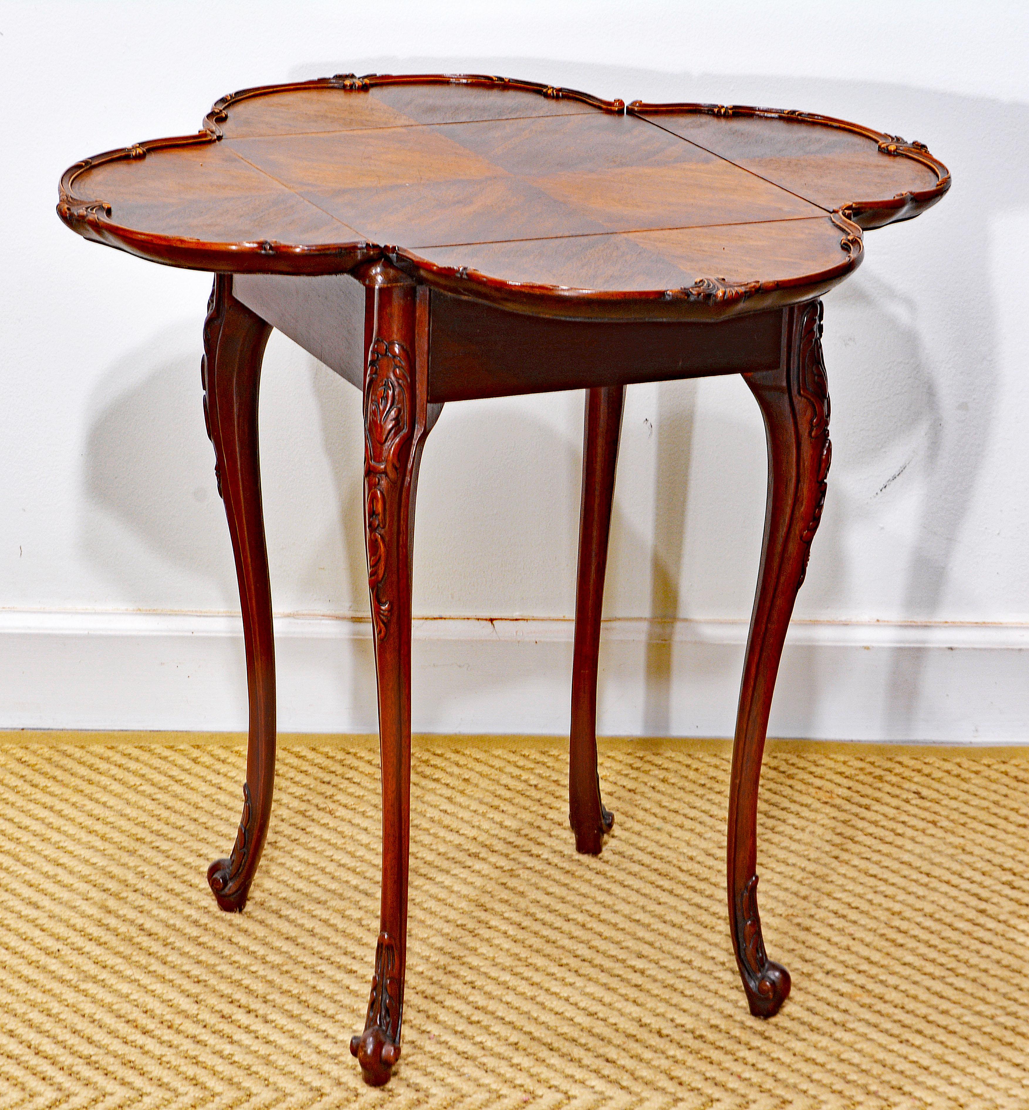This Louis XV style clover shape carved walnut side tale features a quartered veneer table top and dropleaves with foliage carved raised edges above the square frame resting on carved cabriole legs with bulb carved feet in the French tradition. The