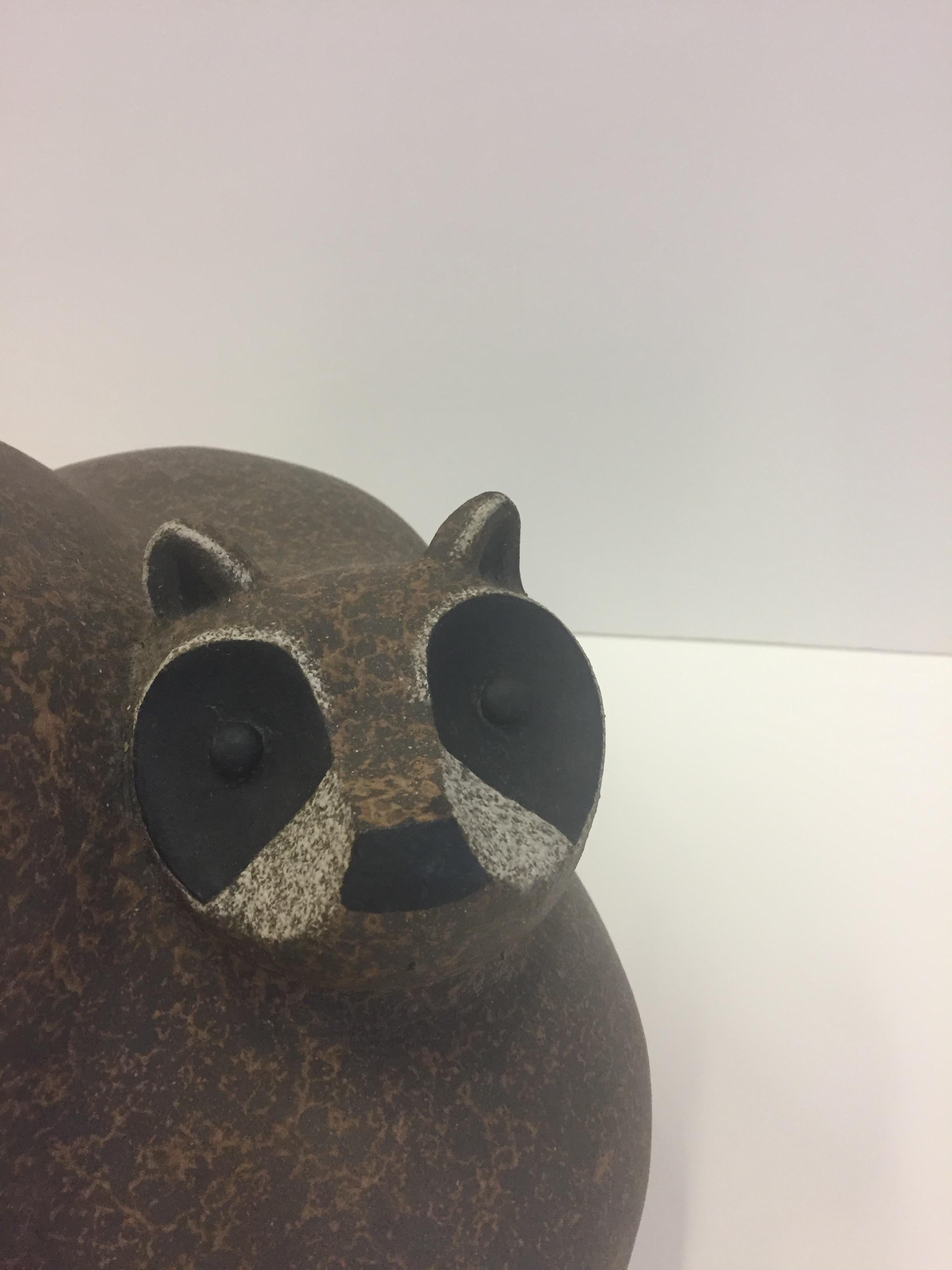 An eye-catching artisan made earthenware sculpture of a stylized mother raccoon and her babies in brown, black and white, signed Jey with a seal on the bottom.
 