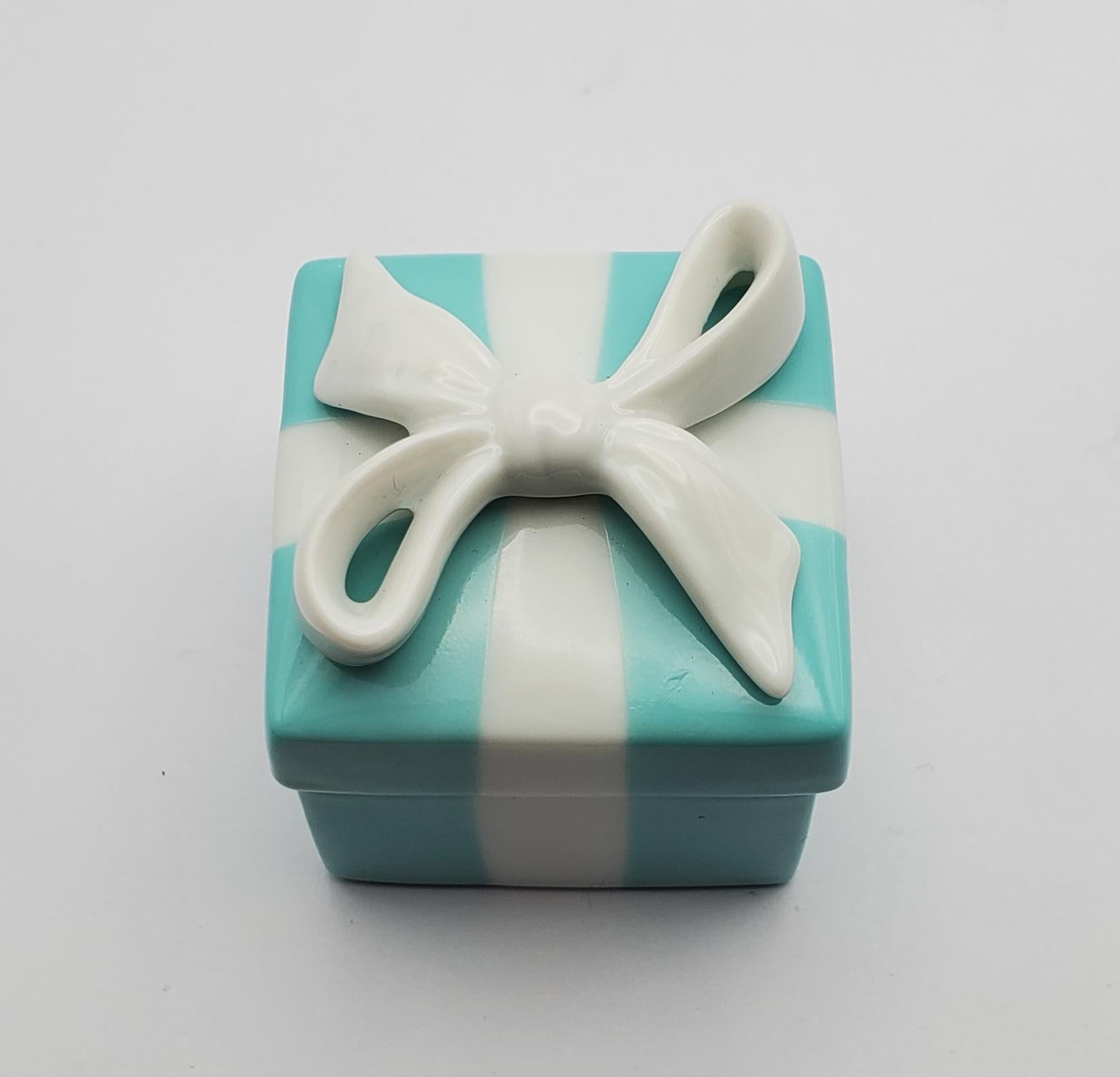 Charming vintage Tiffany & Co. porcelain trinket box. This adorable piece would be beautiful addition to any dresser or vanity. The iconic turquoise blue color with white ribbons and a bow adds a touch of elegance, while the compact size makes it