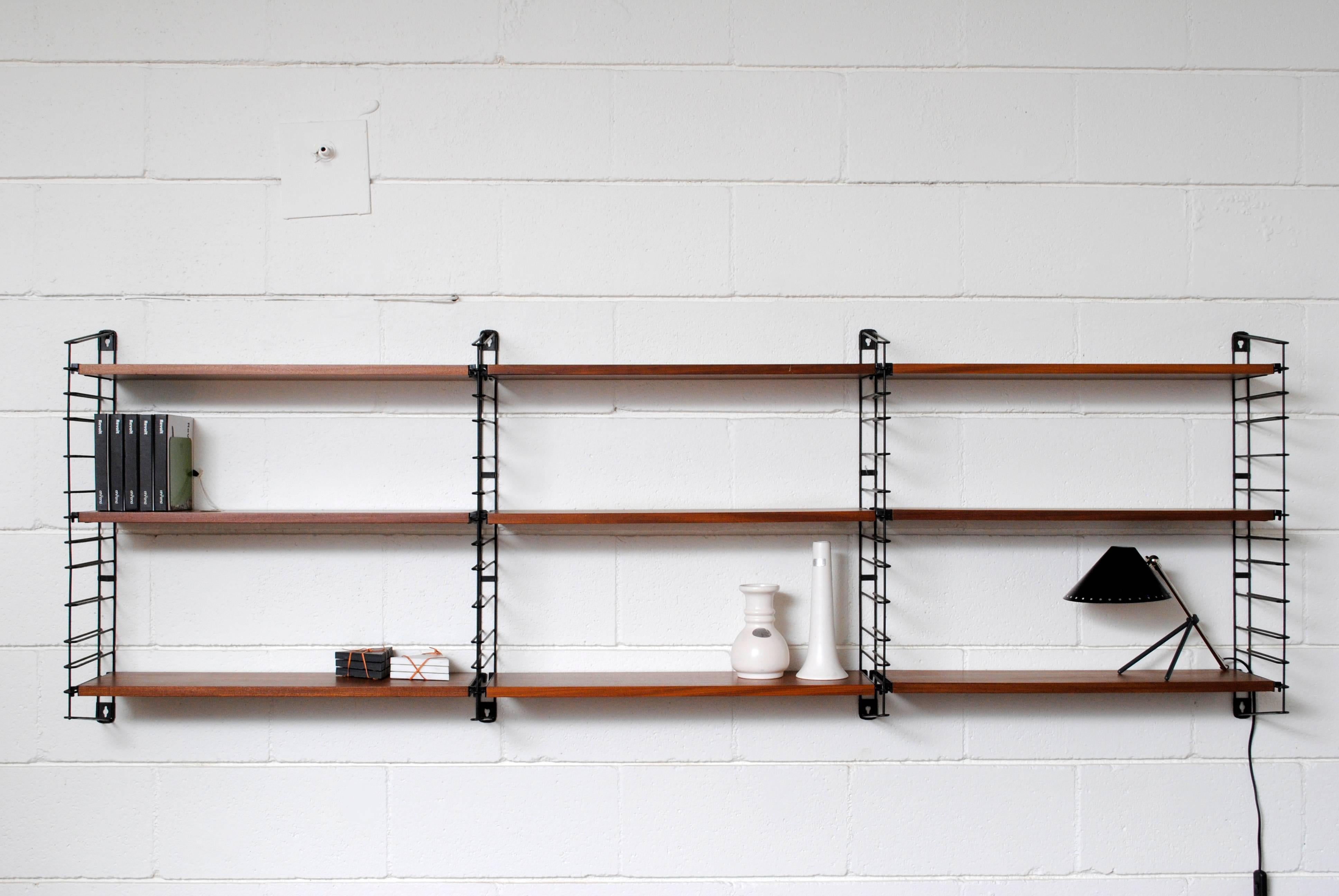 Gorgeous! Tomado industrial wall mount shelving unit with teak shelves and black enameled metal uprights, interchangeable and expandable. Nine shelves. In original condition with visible signs of wear. Can ship or store flat.