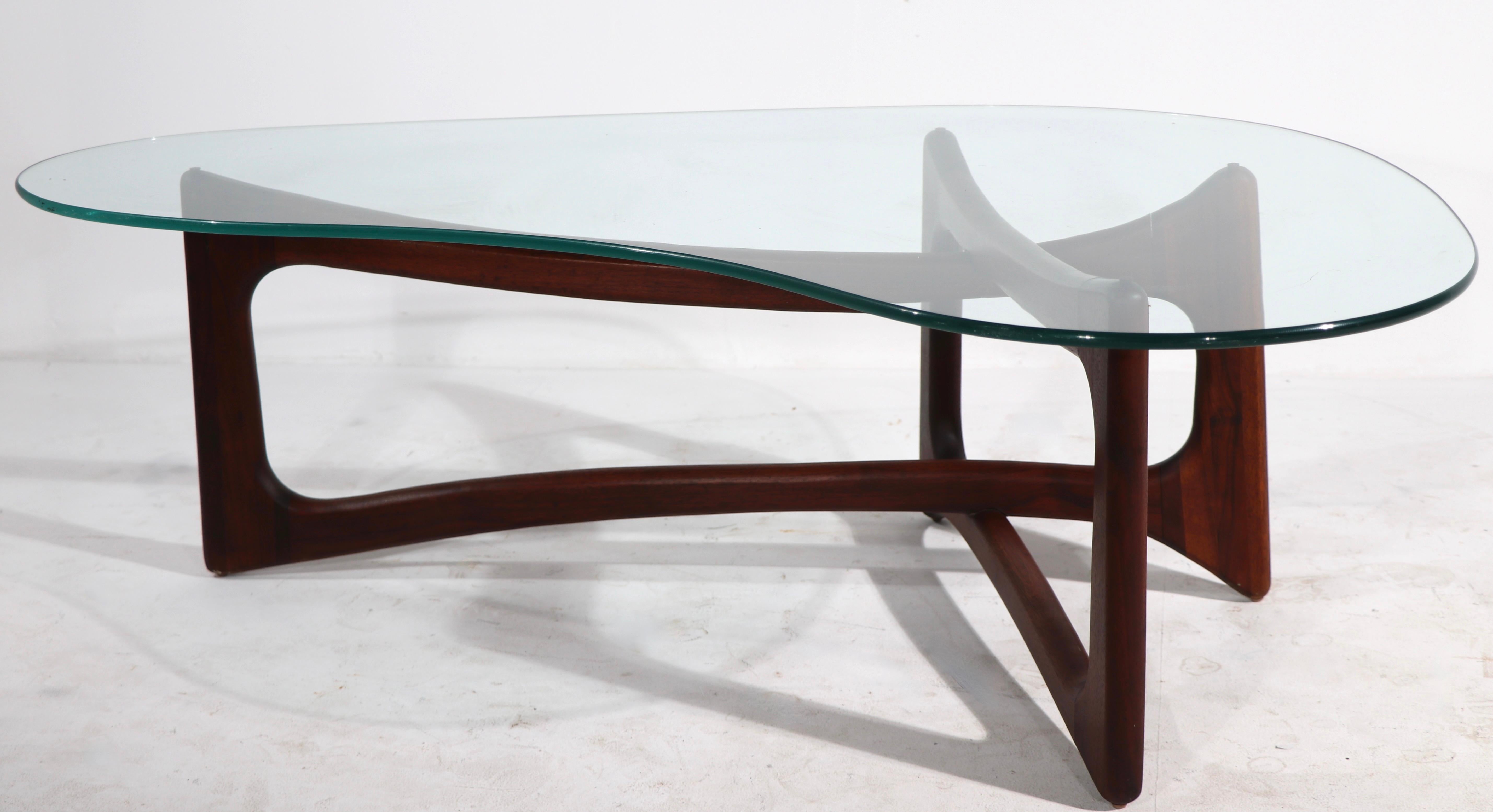 Classic Mid Century free form glass top coffee table designed by Adrian Pearsall for Craft Associates. The table has interlocking organic wood (walnut) elements which support the original amoeba shaped plate glass top (3/8 inch). The table is in