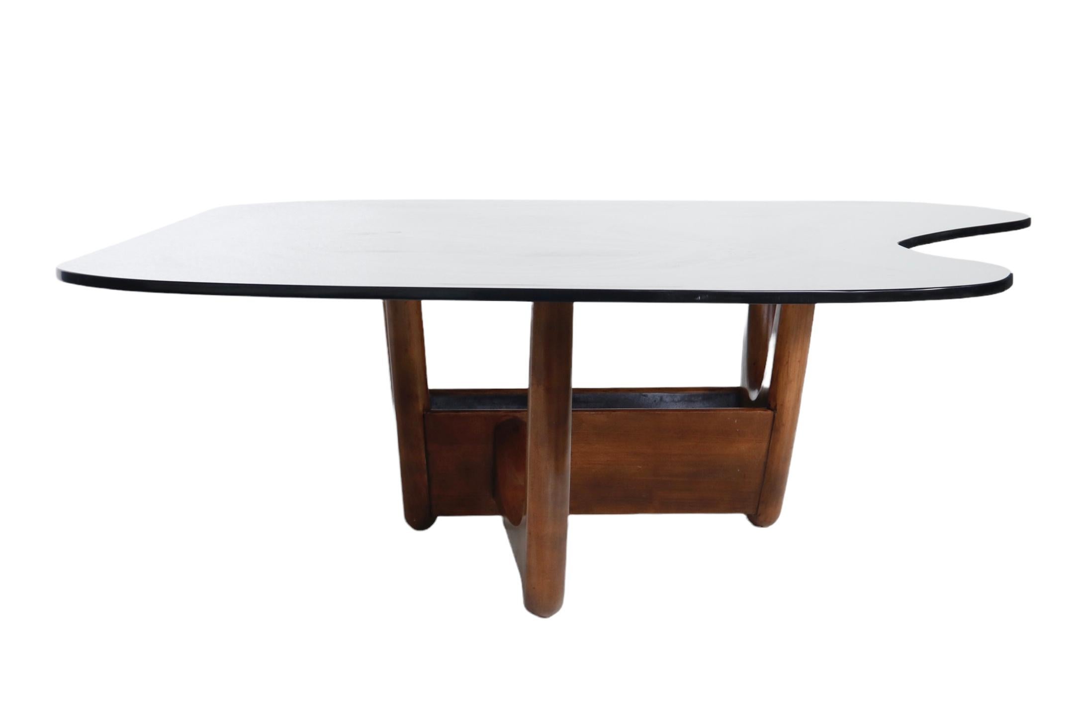 Table basse Adrian Pearsall comportant une base en bois et un plateau en verre fumé personnalisé en forme d'amibe. 

USA, vers 1960.

La base peut être utilisée de deux façons, comme indiqué.

Dimensions :
Overall/Top : 54.5 inches L x 40.5 inches D