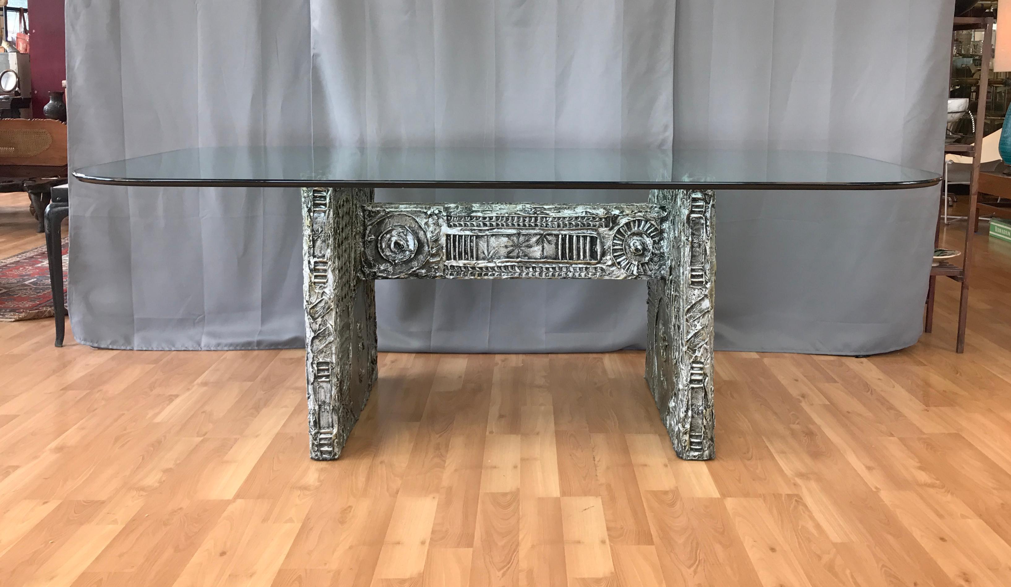 An impressive and less common 1960s Brutalist dining table with glass top by Adrian Pearsall for Craft Associates.

Substantial three-piece wood slab base covered in highly detailed, deep relief, hand sculpted resin with a patinated silver finish.