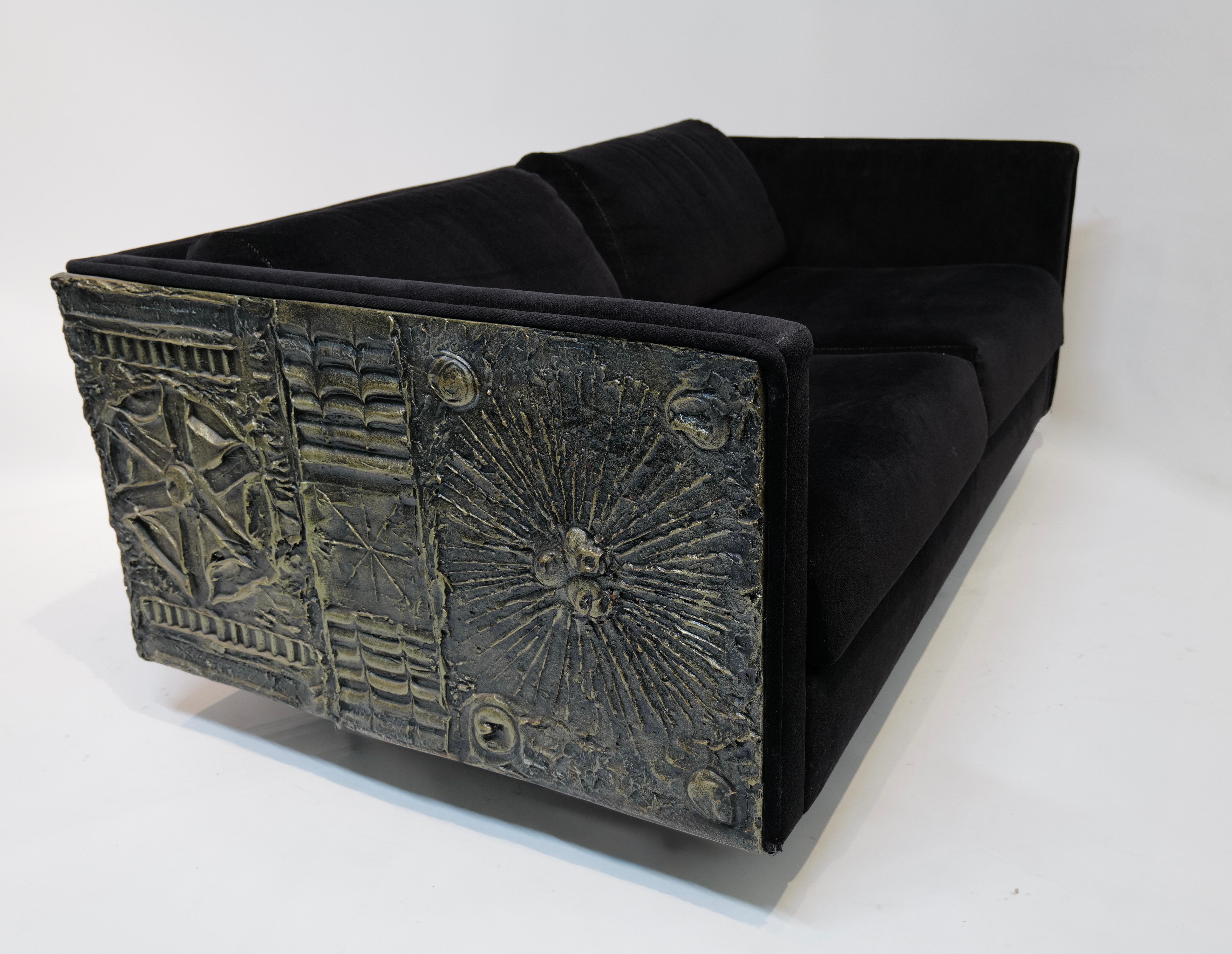 A striking example of Adrian Pearsall’s bold design vision, this two-cushion sofa blends clean modernist lines with dramatic Brutalist detailing. Upholstered in rich black fabric, the low-profile silhouette features squared arms and deep seat