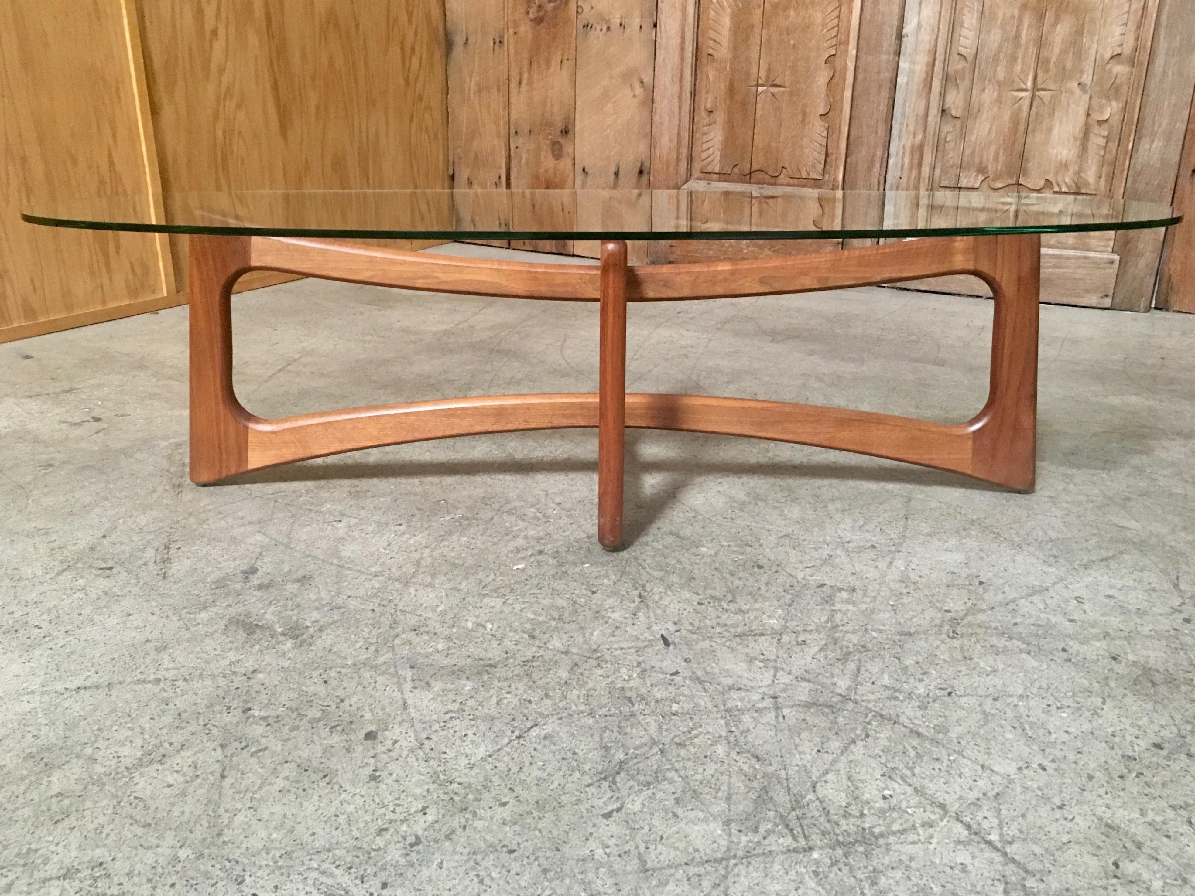 Solid sculpted walnut coffee table base with oval glass top design by Adrian Pearsall for Craft Associates.