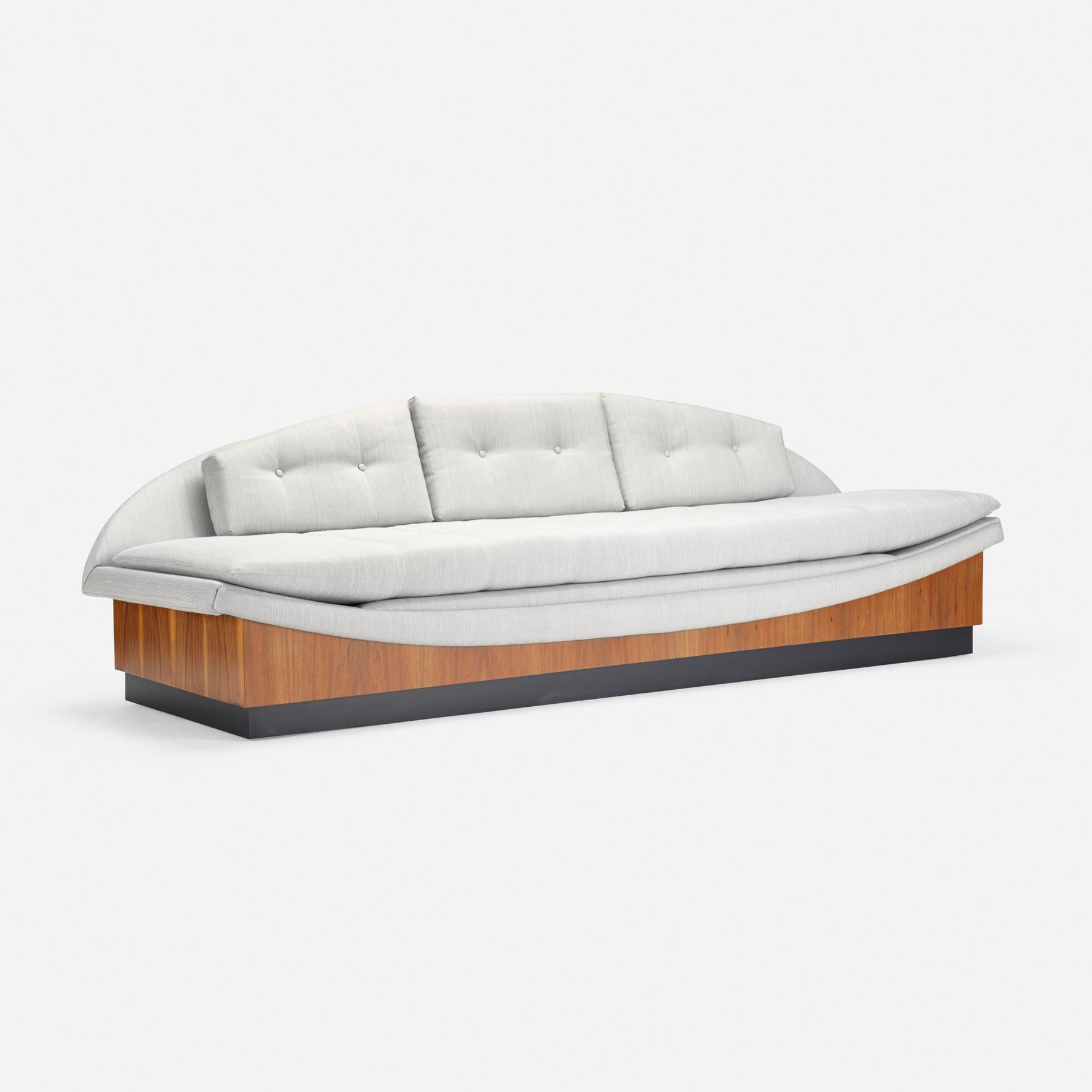 A magnificent seating form is carved into a teak platform which floats atop a black plinth. Designed by Adrian Pearsall for Craft Associates, this floating gondola sofa