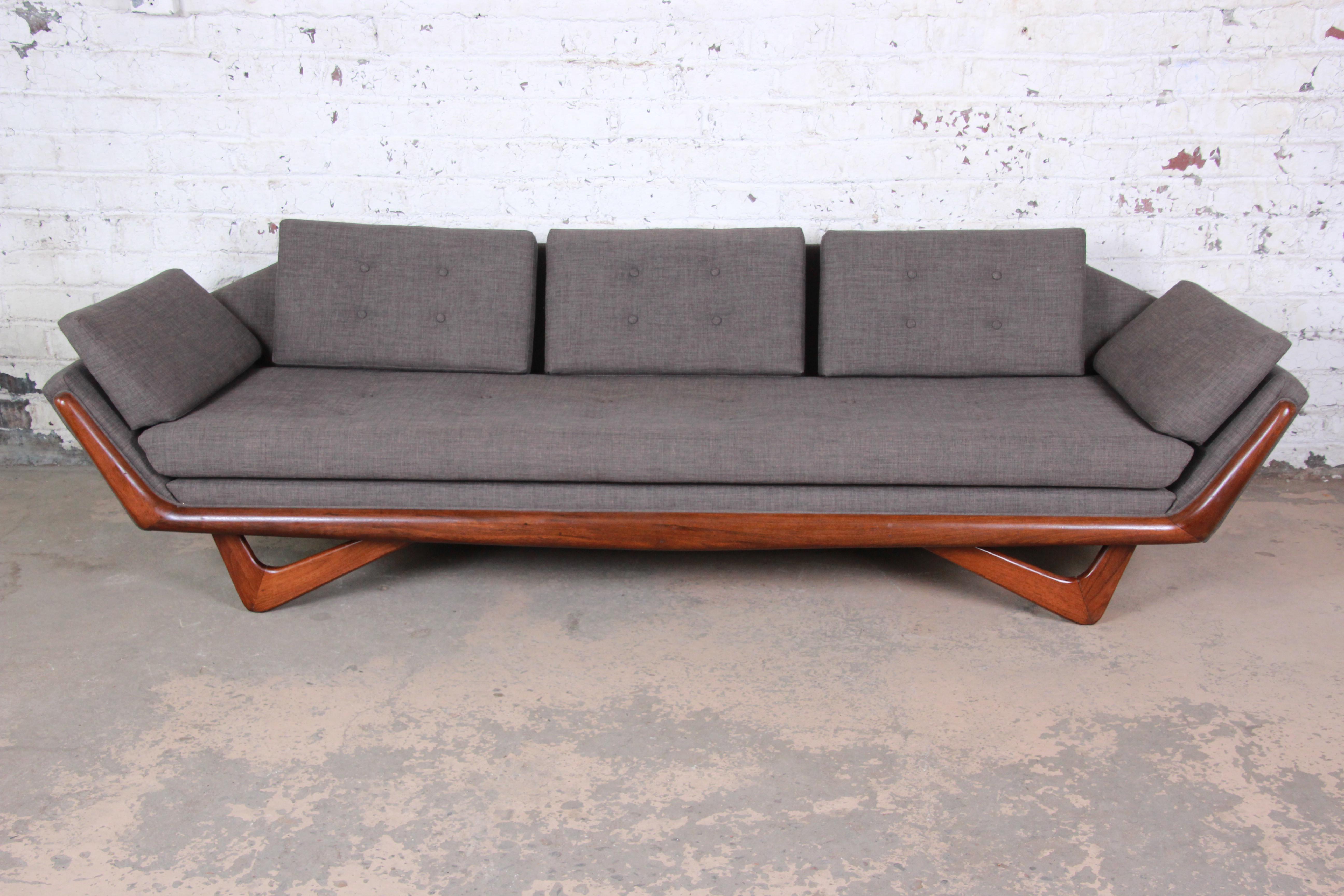 An exceptional Mid-Century Modern gondola sofa designed by Adrian Pearsall for Craft Associates. The sofa features a solid walnut frame and legs, and it has been recently reupholstered in beautiful tufted gray upholstery. This is Pearsall's iconic