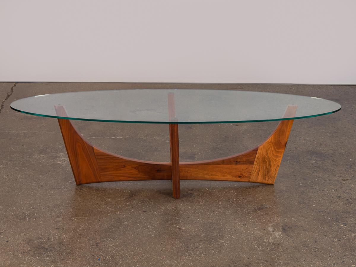 1960s glass coffee table designed by Adrian Pearsall. An organic, dynamic table form. Oval glass is clean with minimal scratches and no chips along the edge. Glass sits on a beautifully sculpted, four legged atomic era base that is thoughtfully