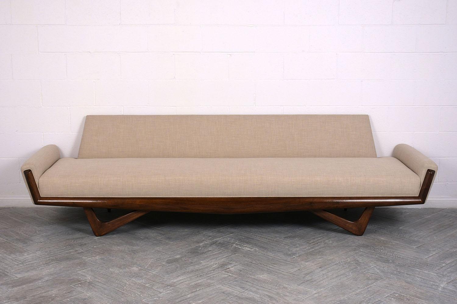 This 1960’s Mid-Century Modern sofa is designed by Adrian Pearsall and has been completely restored. The sofa has been professionally reupholstered in a beige color fabric with single piping trim and topstitch details. The sofa is accompanied by