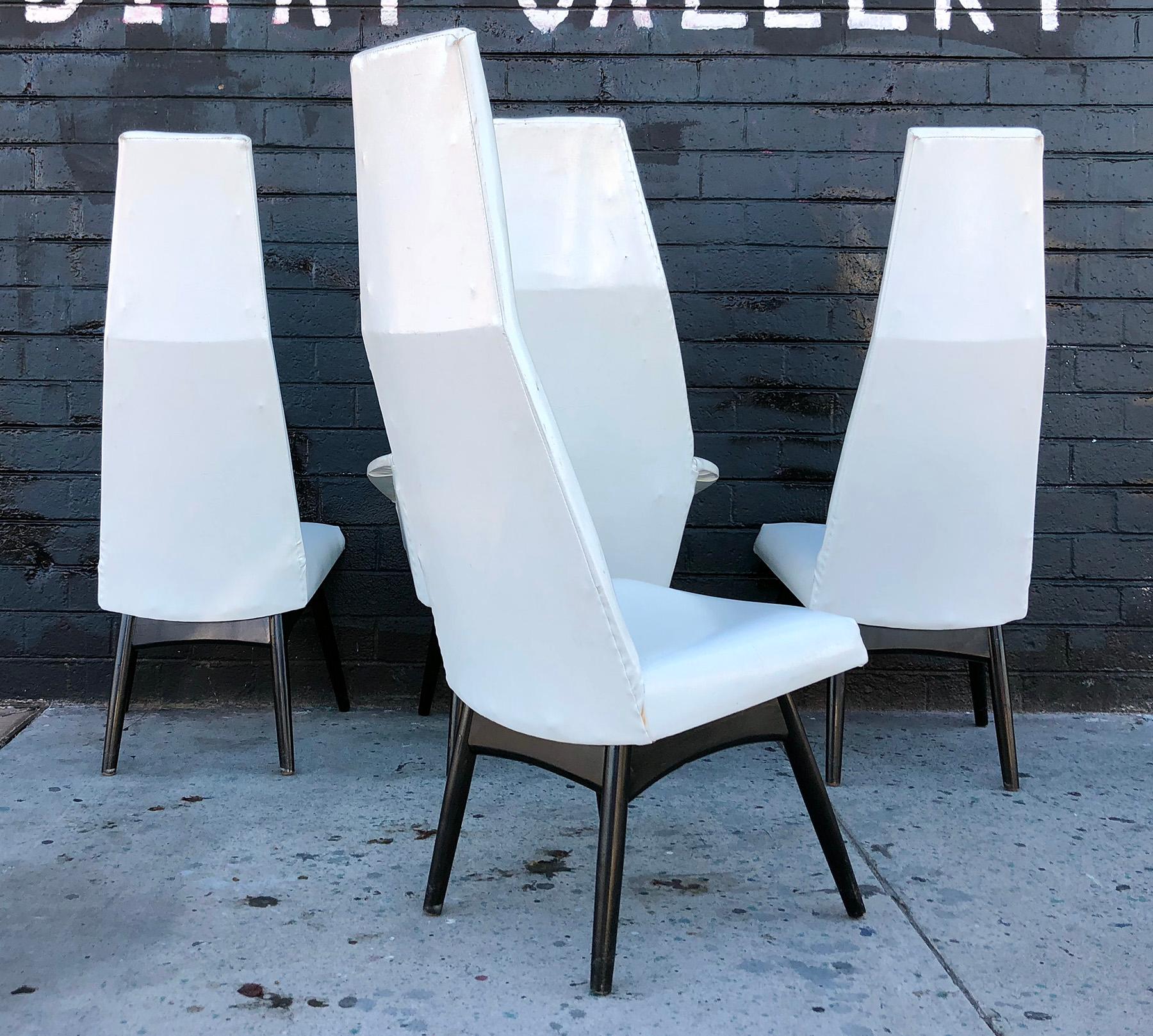 A gorgeous set of Adrian Pearsall high back dining chairs. Each chair is a gorgeous statement piece and is a great piece of sculptural furniture. Three side chairs and 1 captain chair. Chairs are upholstered in their original white vinyl and feature