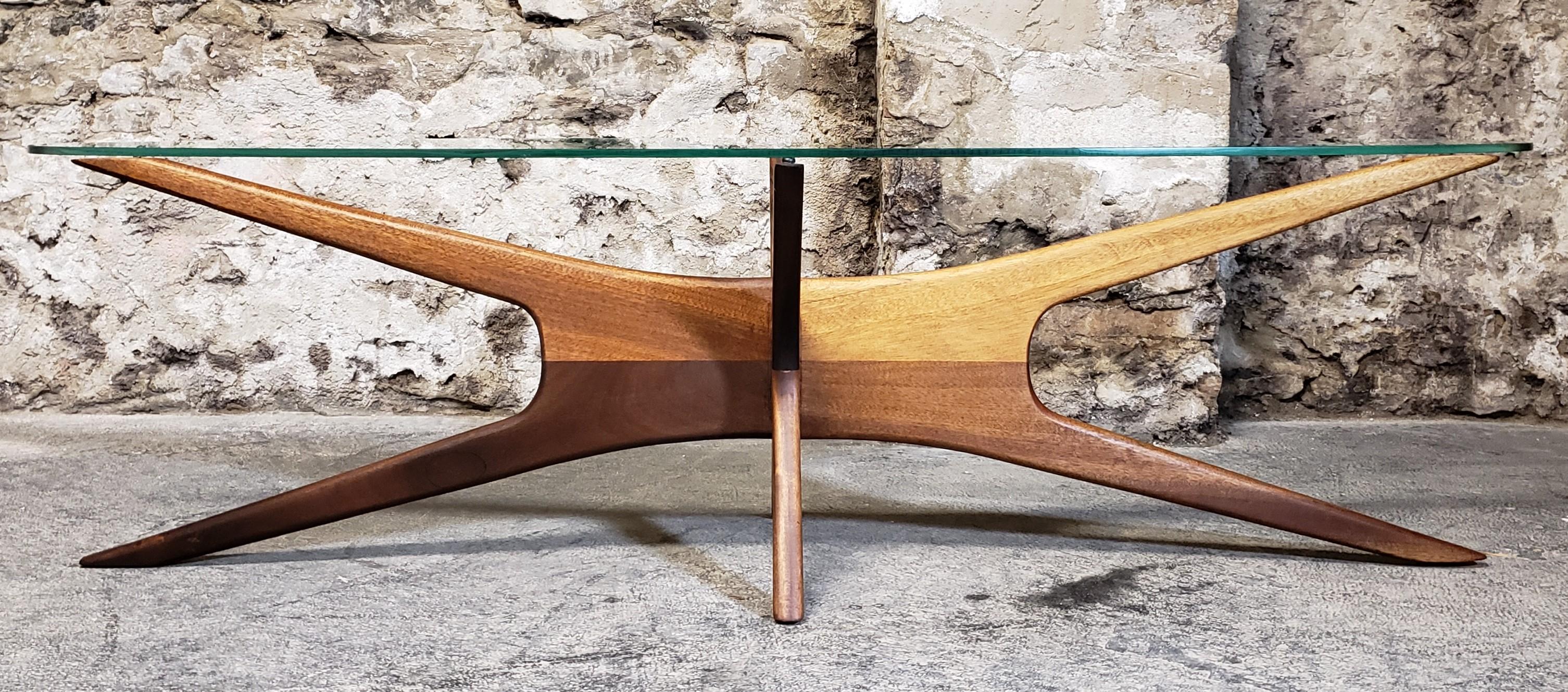 Dating from the 1960s, this iconic “Jacks” mid-century modern coffee table was designed by Adrian Pearsall for Craft Associates. It features a modernist sculpted walnut base with a heavy oval glass top.