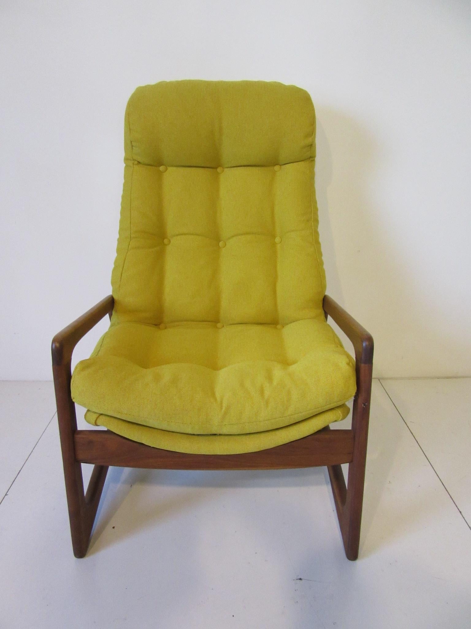 A sculptural solid walnut framed comfy lounge chair upholstered in a muted yellow fabric with button back and bottom details plus a built in headrest. A great form from the period by the American designer and craftsman Adrian Pearsall, manufactured