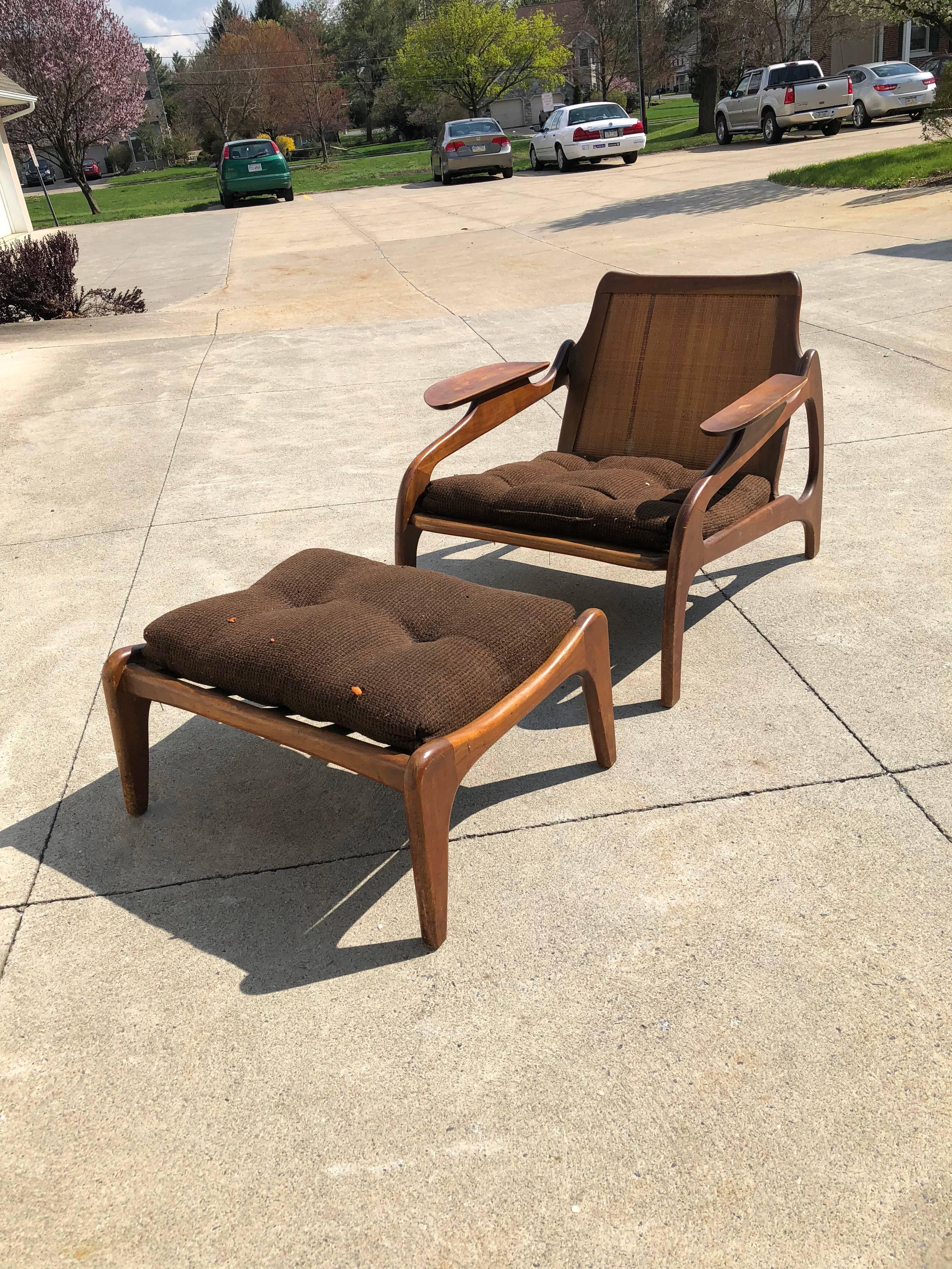 Very comfortable low slung lounge chair, model 1209c designed by Adrian Pearsall and made by Craft Associates. This chair and ottoman have solid walnut sculpted frame loose cushions an canned back.