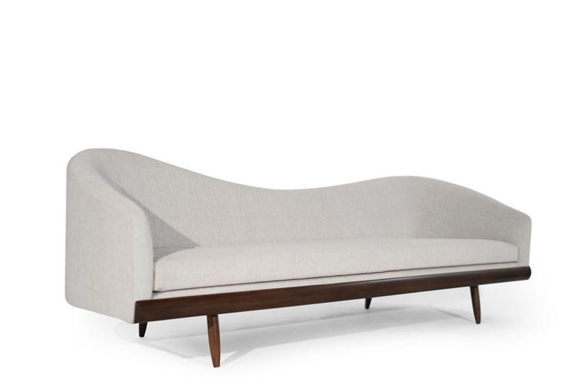 Adrian Pearsall Oasis Sofa, a mid-century masterpiece now restored by Stamford Modern. Designed in the 1950s, it features organic curves, and walnut details, reupholstered in grey velvet. This iconic sofa blends timeless elegance with modern