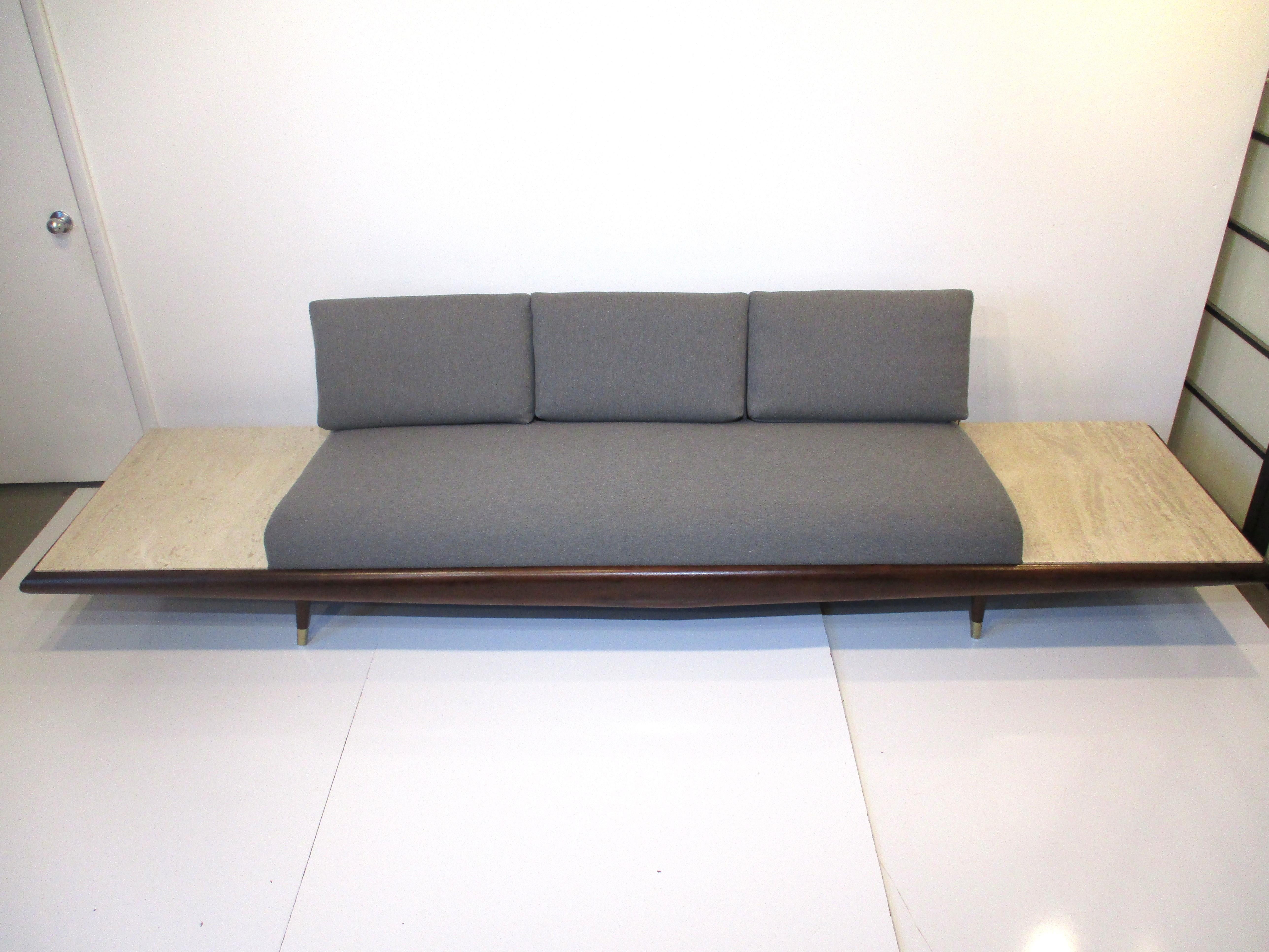 A very well constructed Mid Century platform sofa with built in floating marble end tables . There is a supportive back to the sofa and three loose cushions for comfort all in a soft medium gray contract fabric . A dark walnut frame enhances the