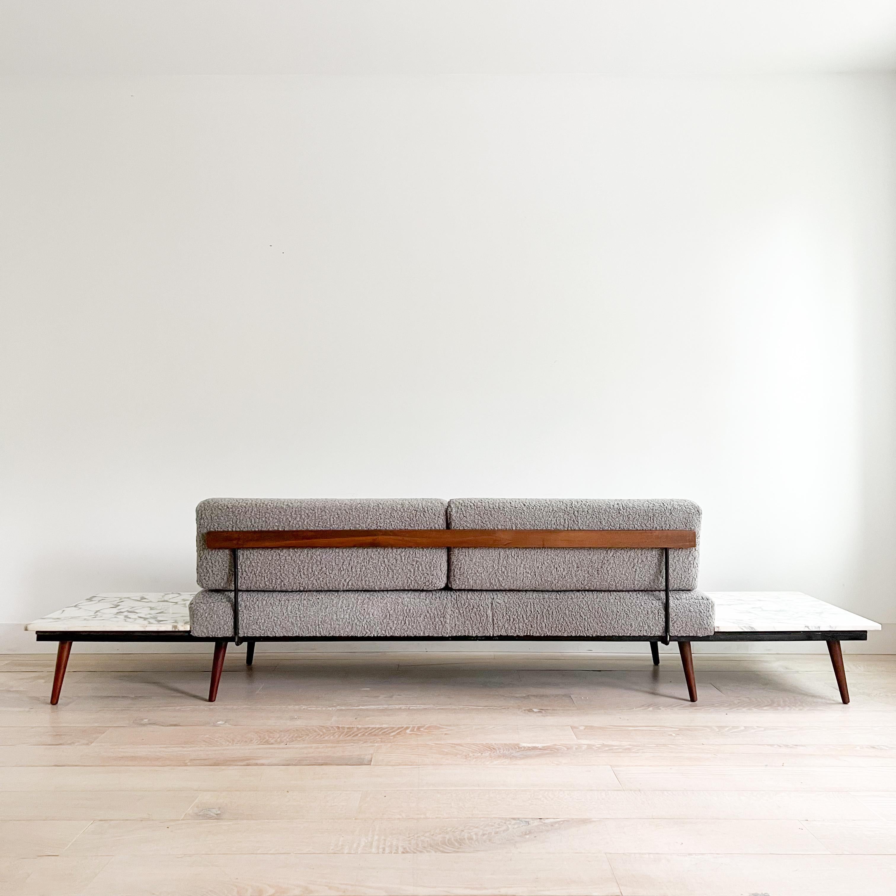 This stunning mid-century modern gondola sofa by Adrian Pearsall features built-in marble end tables. Recently updated with new foam and luxurious grey shearling upholstery. The wooden trim and legs show light scuffing and scratching, consistent