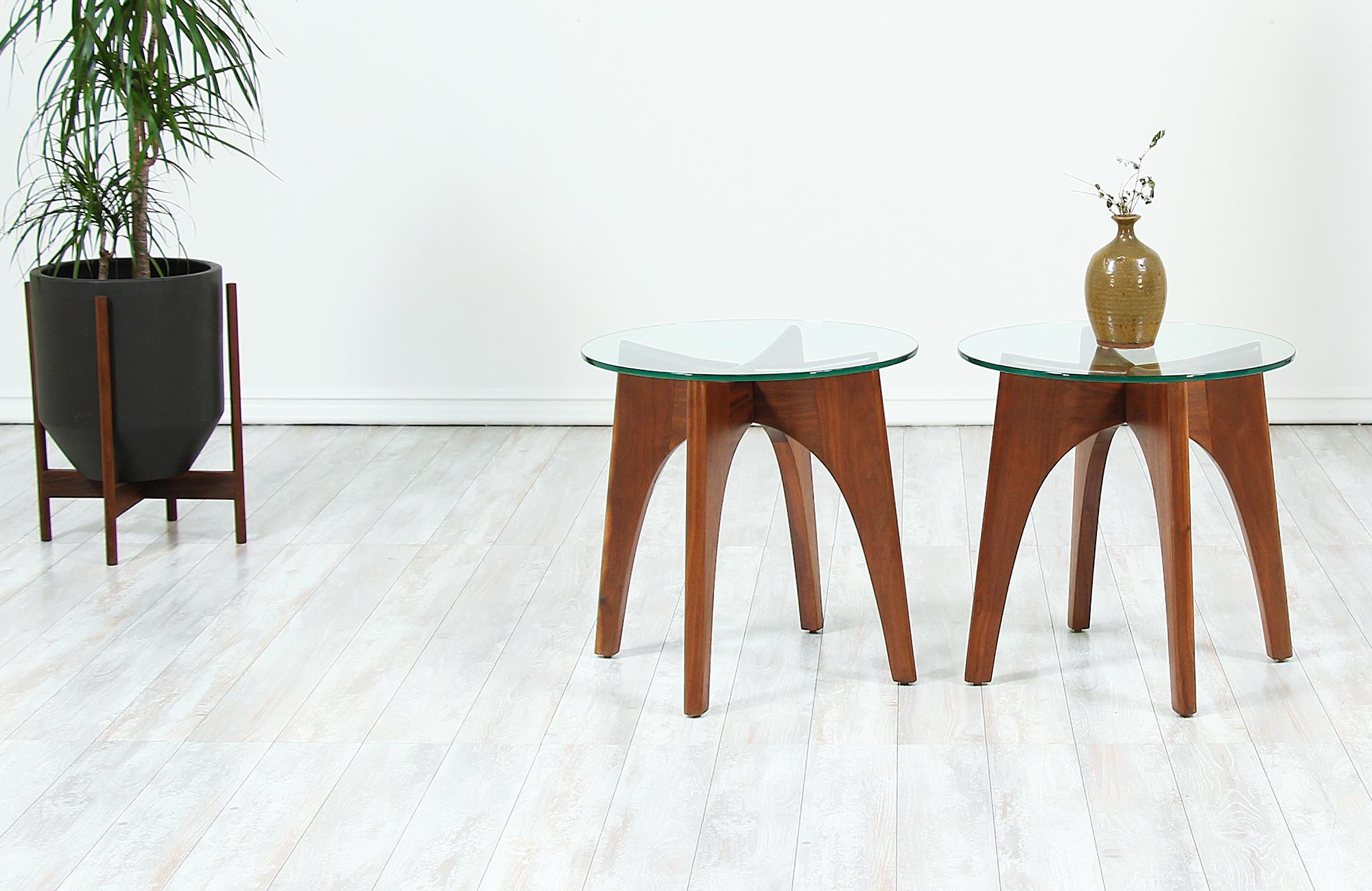 Pair of sculpted side tables designed by Adrian Pearsall for Craft Associates in the United States, circa 1960s. These beautiful side tables feature an ‘X’ shaped walnut wood frame with an interlocked solid base that tightly holds the new circular