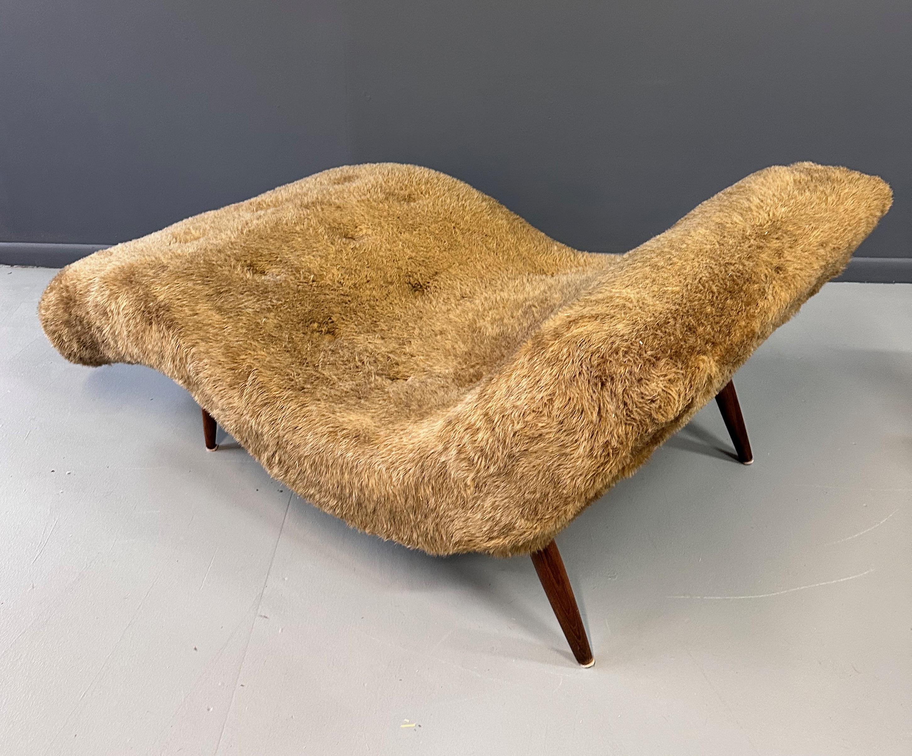 Adrian Pearsall style louge chair in a wonderful wave form with slender oak legs. Generously proportioned, this chair cozily holds two! The chair is presently upholstered in a fun faux fur that is in good shape. 

We are very happy to upholster this