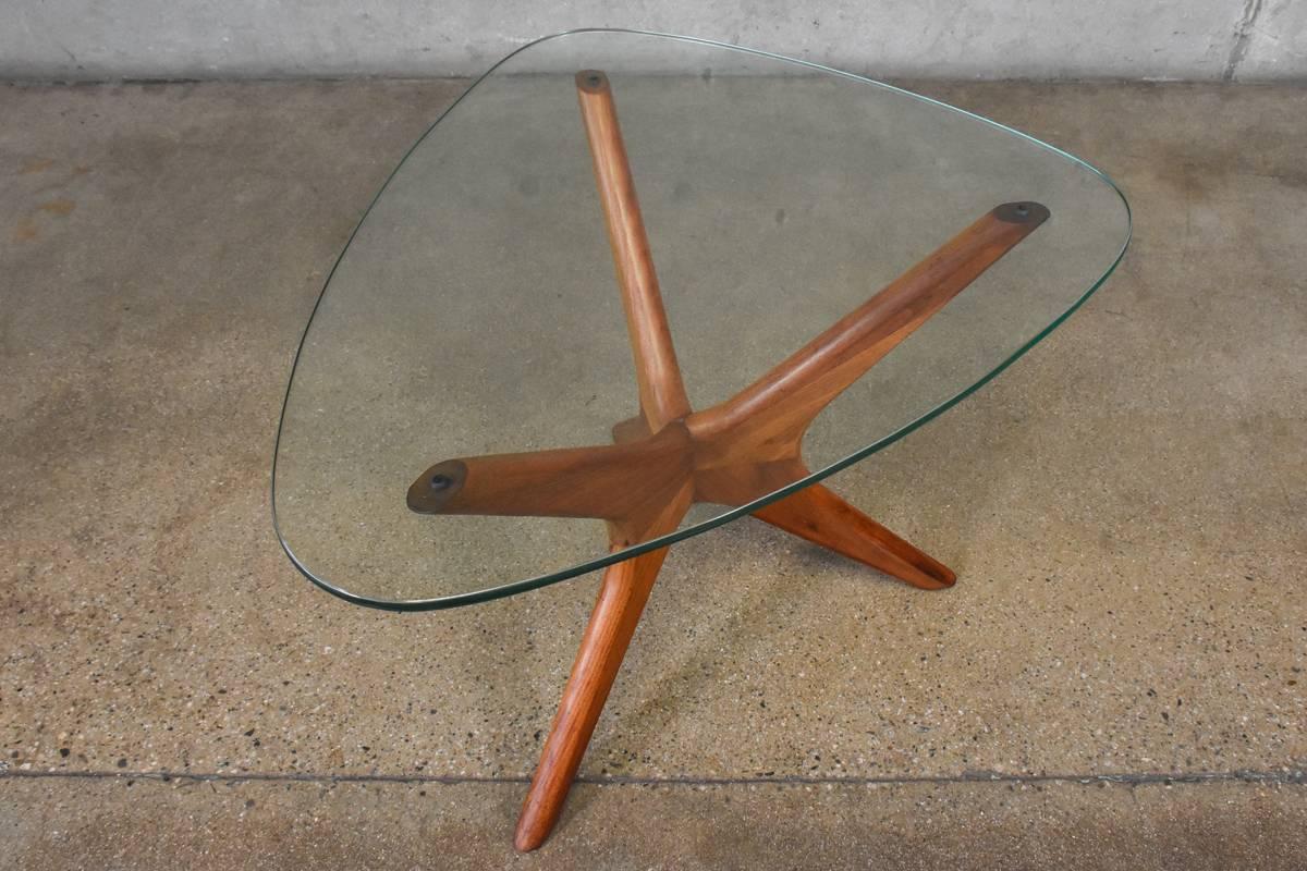 A solid walnut and glass side table designed by Adrian Pearsall for Craft Associates. This table has a tri-symmetric form with one leg slightly longer than the other two. Retains its original glass. This piece is in original condition, so there some