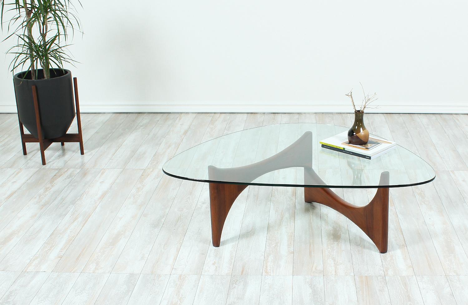 Elegant coffee table designed by Adrian Pearsall for Craft Associates in the United States circa 1960s. This design features a new triangular-shaped glass top with rounded edges that sits over the sculptural walnut wood base. The base rotates and