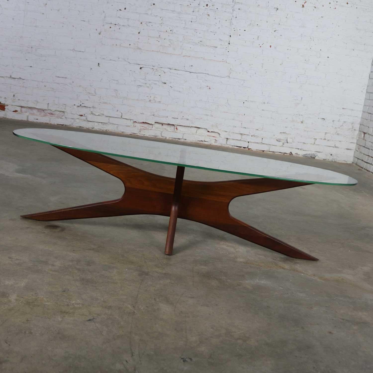 Handsome and iconic walnut and oval glass Mid-Century Modern jacks shaped base coffee table. It is the 893-TGO coffee table design by Adrian Pearsall for his company Craft Associates. This table is in wonderful vintage condition overall with the