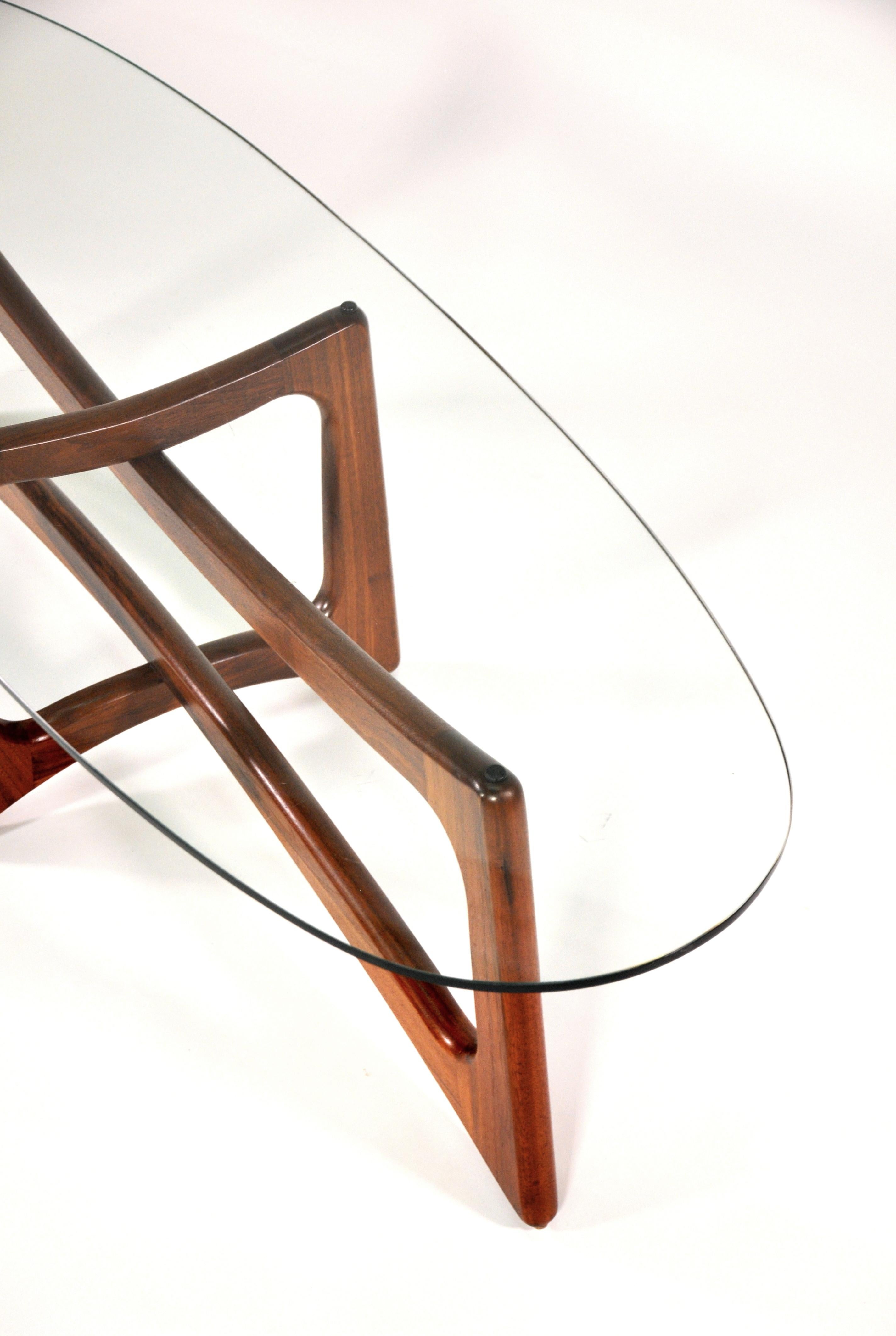 Iconic Mid-Century Modern sculptural walnut and glass cocktail table, model 2454-TGO, designed by Adrian Pearsall for Craft Associates, Inc. in the 1960s. The interlocking solid walnut base is topped by an oval glass. The sculptured wood is richly
