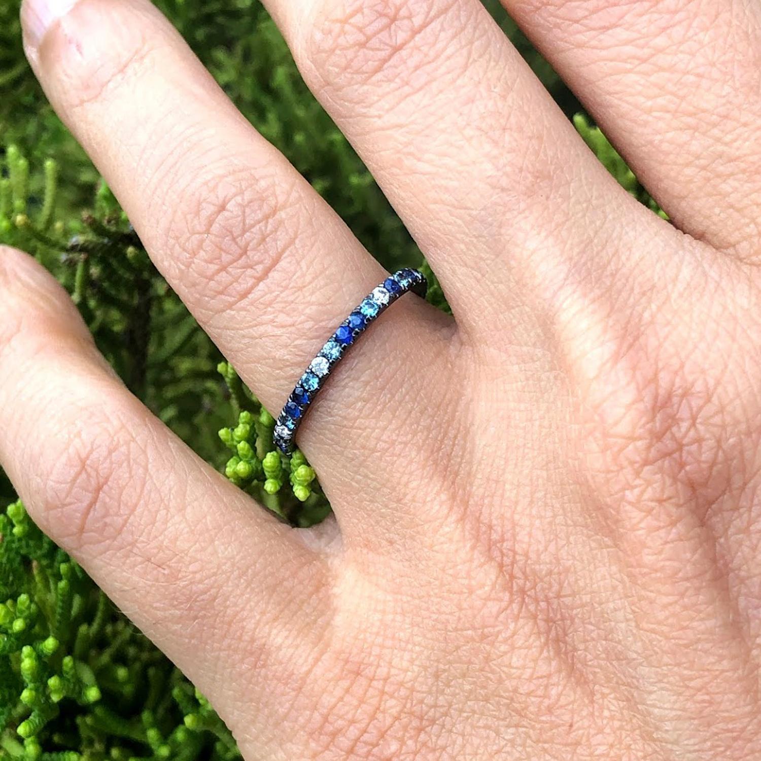 Evoking the blue tones of the Adriatic Sea, this mixed eternity band features varying tones of blue topaz, bluish grey sapphire, blue sapphire, grey diamonds & white diamonds. 

Total carat weight: 0.6 (for size 6)
Total width: 1.8mm (1.5mm
