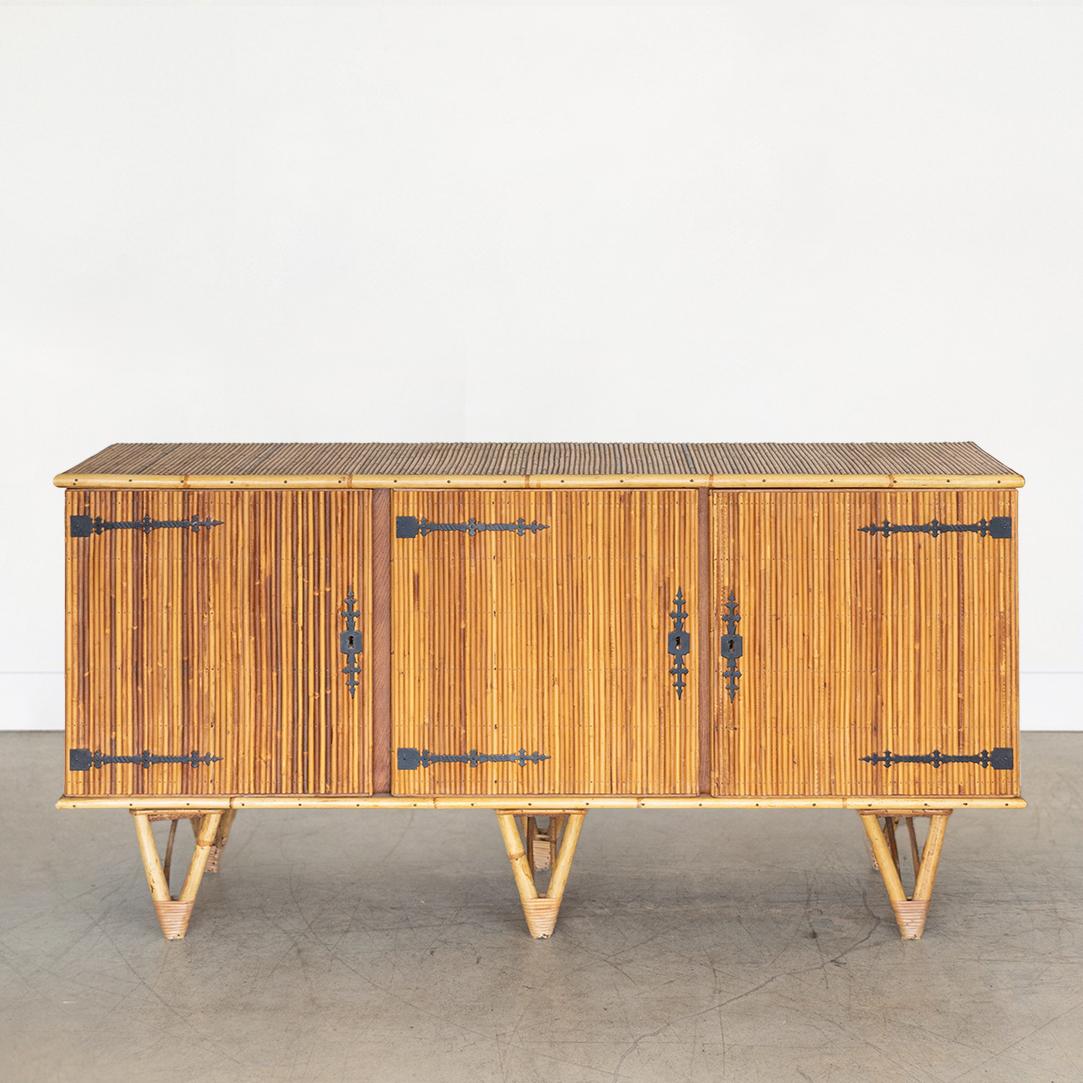 Beautiful split bamboo sideboard by Adrien Audoux and Frida Minet from France, 1960's. Three-door cabinet with intricate wrought iron hinges, interior shelf, and original key. Thick triangular bamboo legs with wrapped rattan detail. Original finish