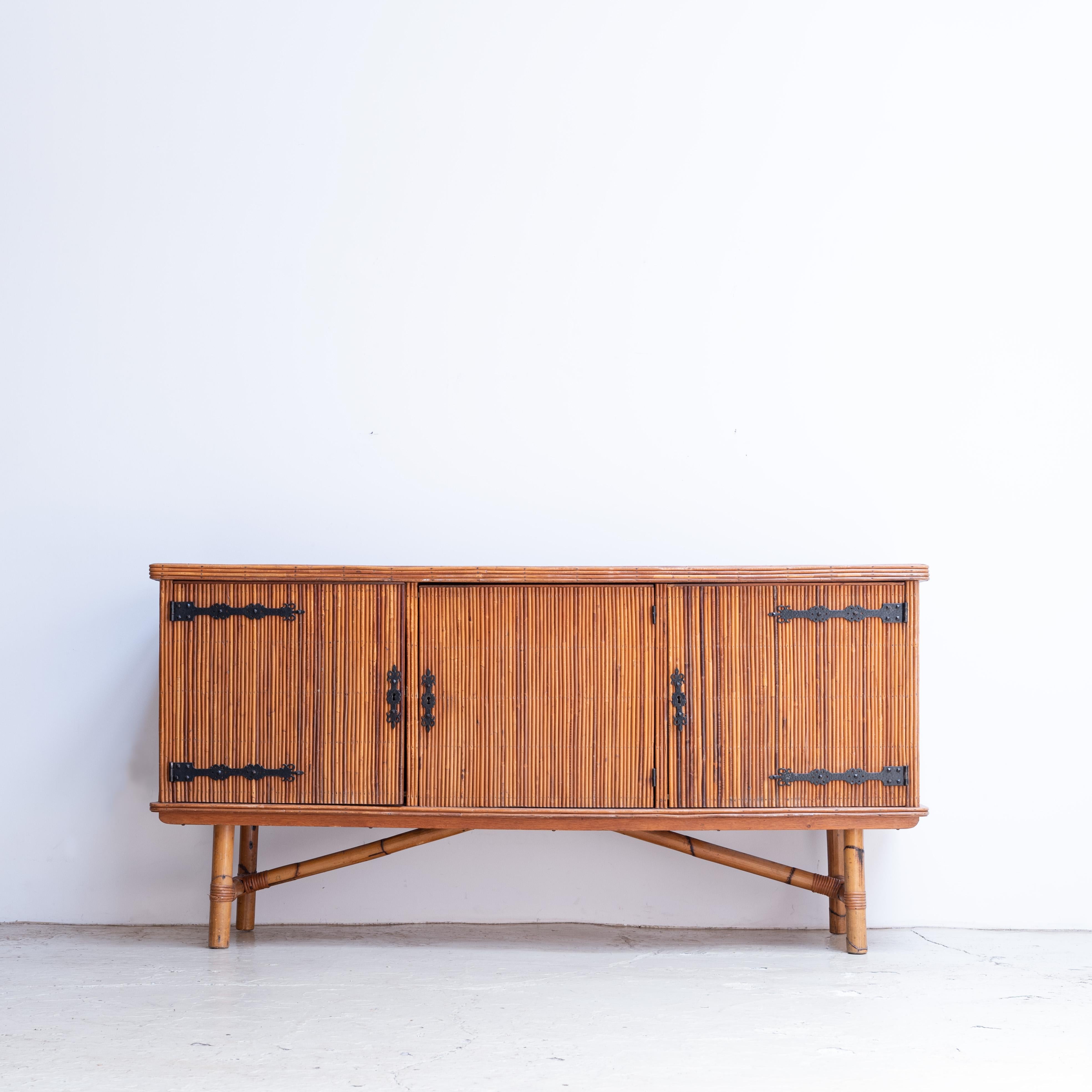 Bamboo sideboard designed by French designer duo Adrien Audoux & Frida Minet. Circa 1960s.
Three doors that have decorative wrought iron hinges. An original key to open and close the cabinet doors.

Dimensions: 181 x 51 x 90.5 cm
The size of the